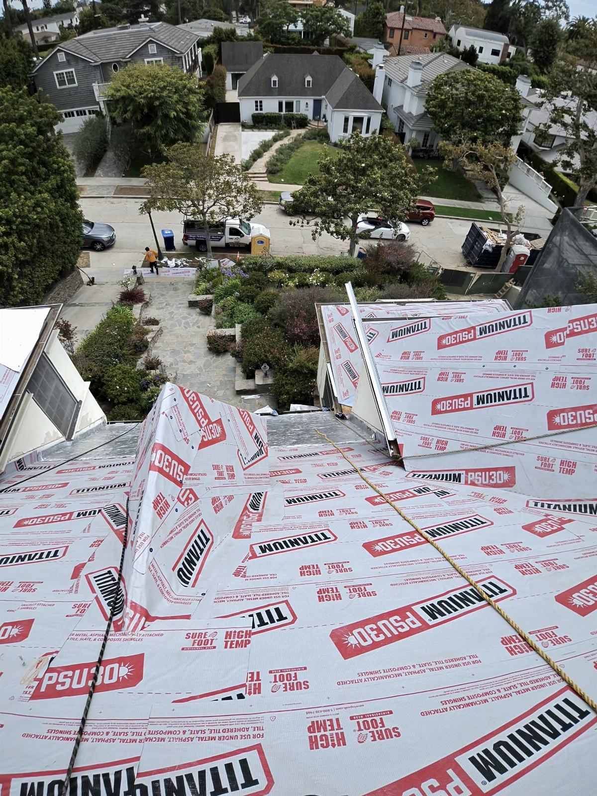 Steep roof deck covered with Titanium PSU30 underlayment, rope safety lines visible | Roof Replacement Inc Steep roof deck covered with Titanium PSU30 underlayment, rope safety lines visible — Roof Replacement Inc