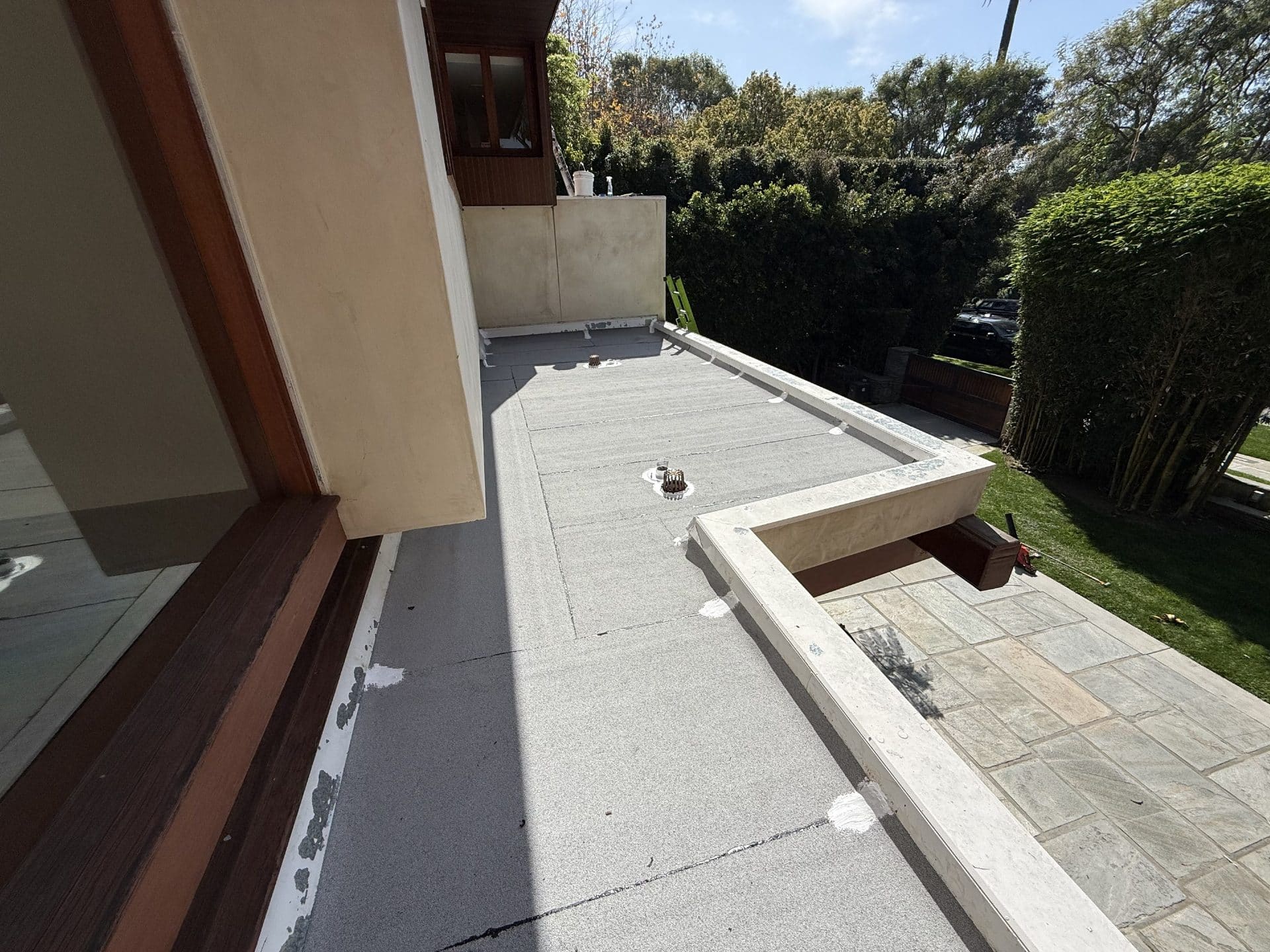 Flat roof with torch-down membrane, drain, and stone parapet wall in Beverly Hills | Roof Replacement Inc flat roof with torch-down membrane, drain, and stone parapet wall — Beverly Hills — Roof Replacement Inc