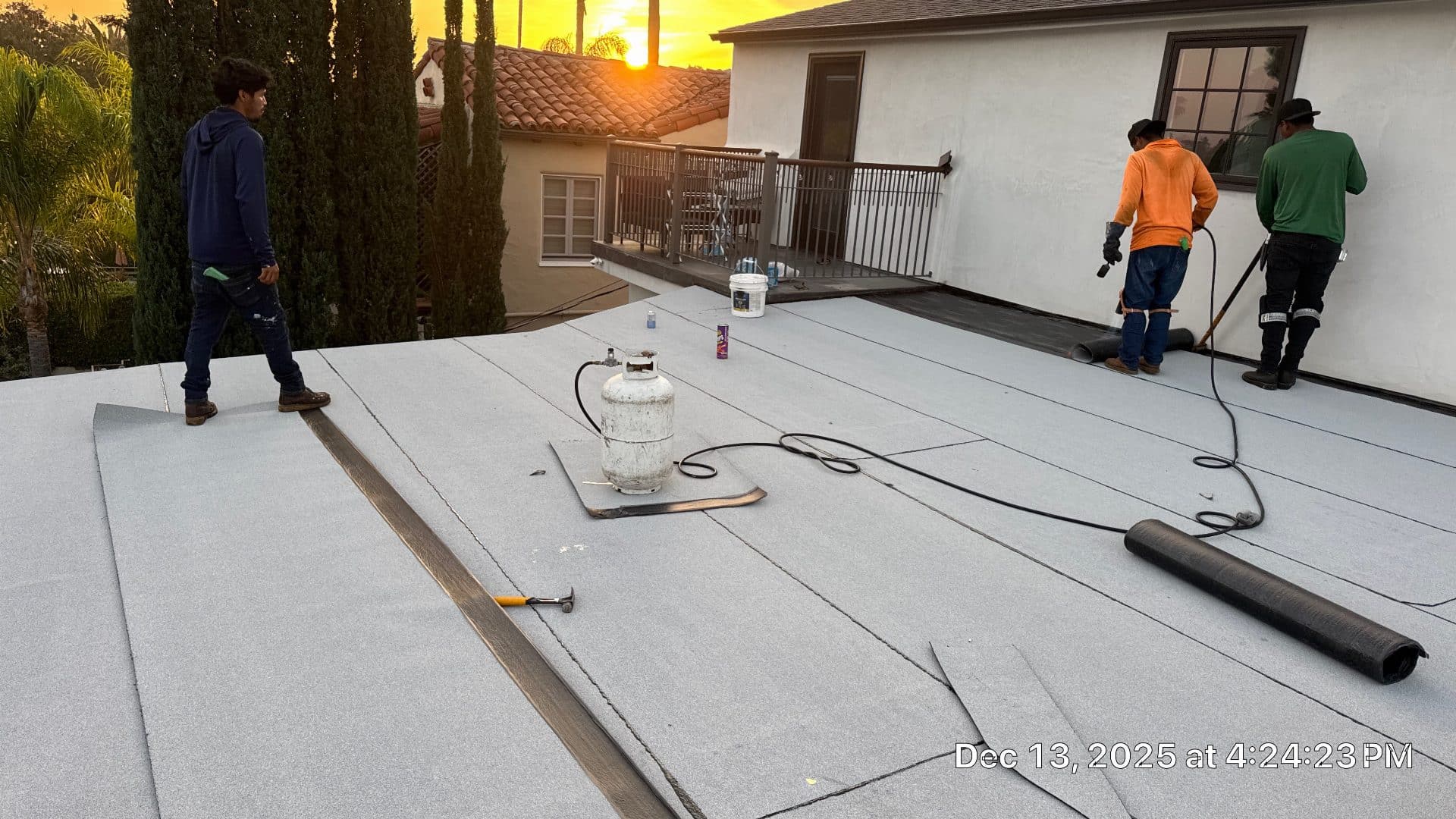 workers torch-applying modified bitumen rolls on flat roof at sunset — Glendale — Roof Replacement Inc