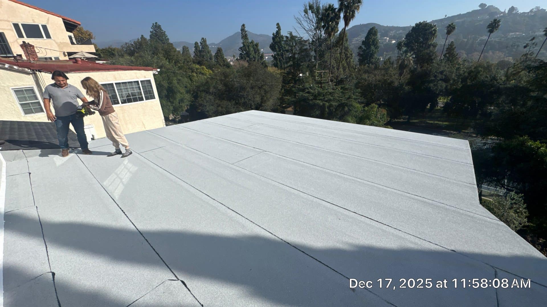Two workers inspecting completed white flat roof membrane in Glendale | Roof Replacement Inc Two workers inspecting completed white flat roof membrane — Glendale — Roof Replacement Inc