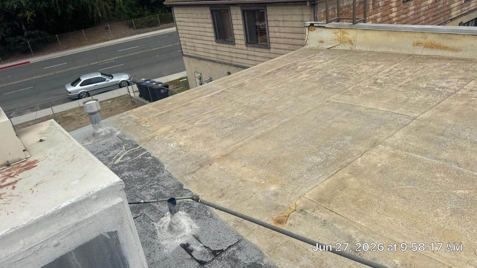 White cool roof coating on a flat residential roof in Southern California summer sunlight