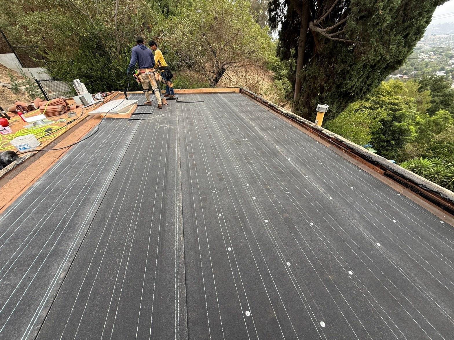 Roof coating materials and application tools staged on a flat roof surface ready for a California coating project