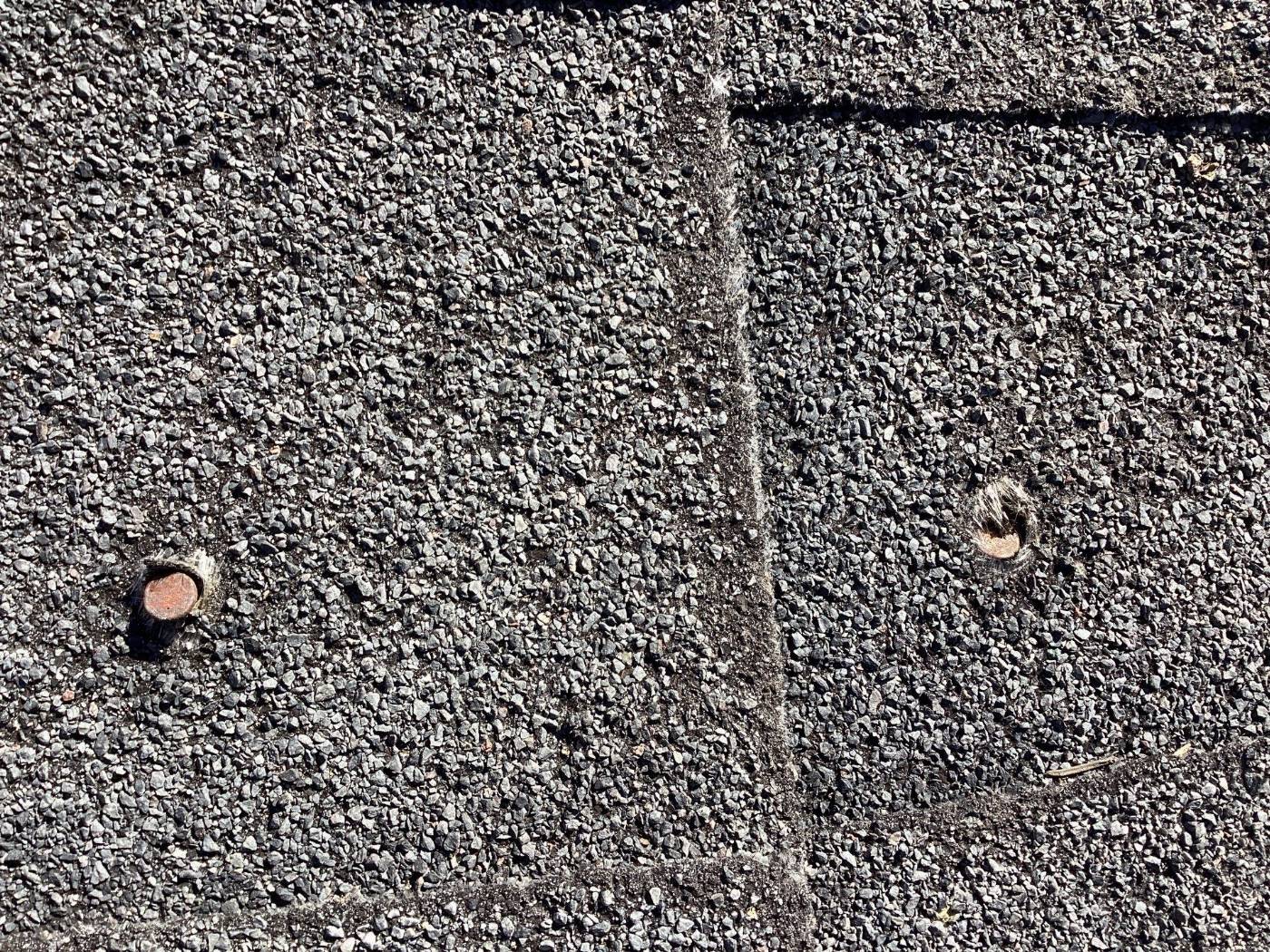 Asphalt shingle roof surface with exposed roofing nails and seams — Roof Replacement Inc