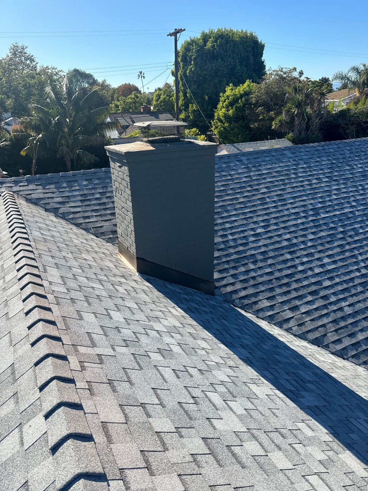 Gray asphalt shingle roof with painted brick chimney, valley junction in Mar Vista | Roof Replacement Inc Gray asphalt shingle roof with painted brick chimney, valley junction — Mar Vista — Roof Replacement Inc