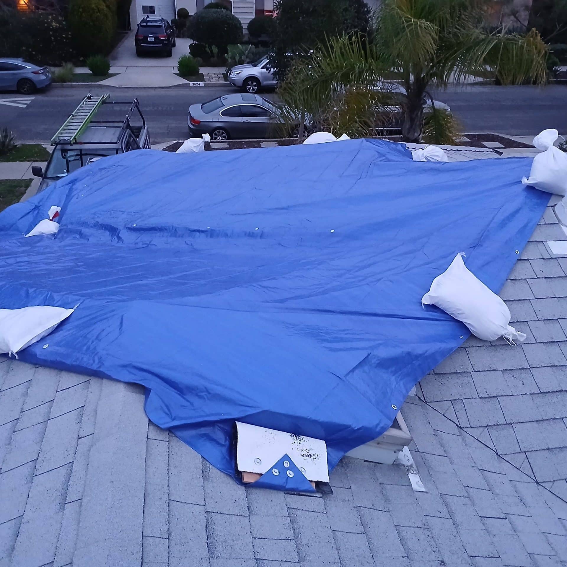 Blue tarp with sandbags securing damaged asphalt shingle roof section — Mar Vista — Roof Replacement Inc