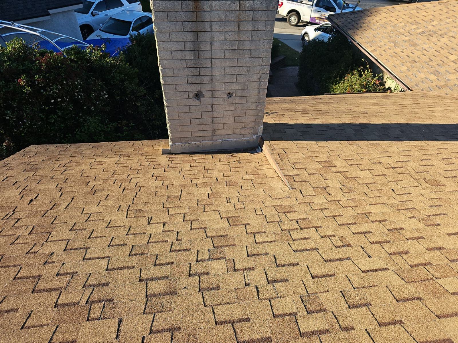 Brick chimney base meeting asphalt shingle roof, missing flashing in Santa Clarita | Roof Replacement Inc Brick chimney base meeting asphalt shingle roof, missing flashing — Santa Clarita — Roof Replacement Inc