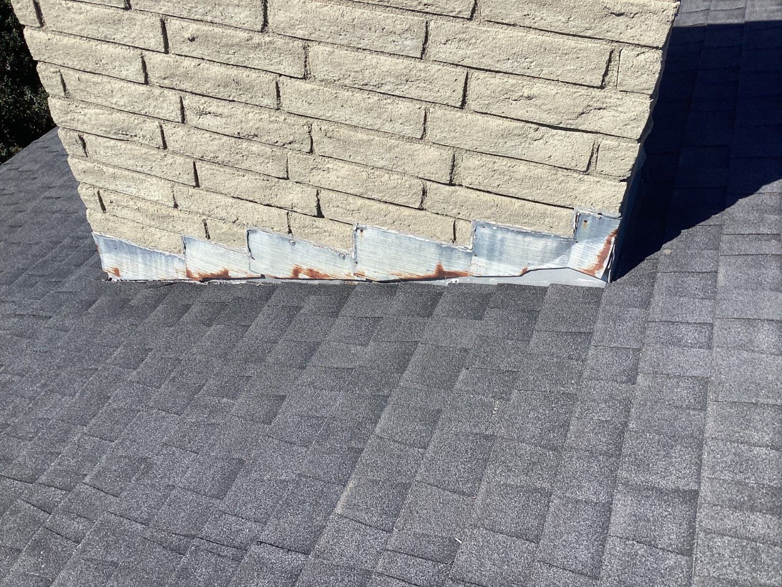 Rusted step flashing at chimney-to-asphalt-shingle roof junction in Granada Hills | Roof Replacement Inc Rusted step flashing at chimney-to-asphalt-shingle roof junction — Granada Hills — Roof Replacement Inc