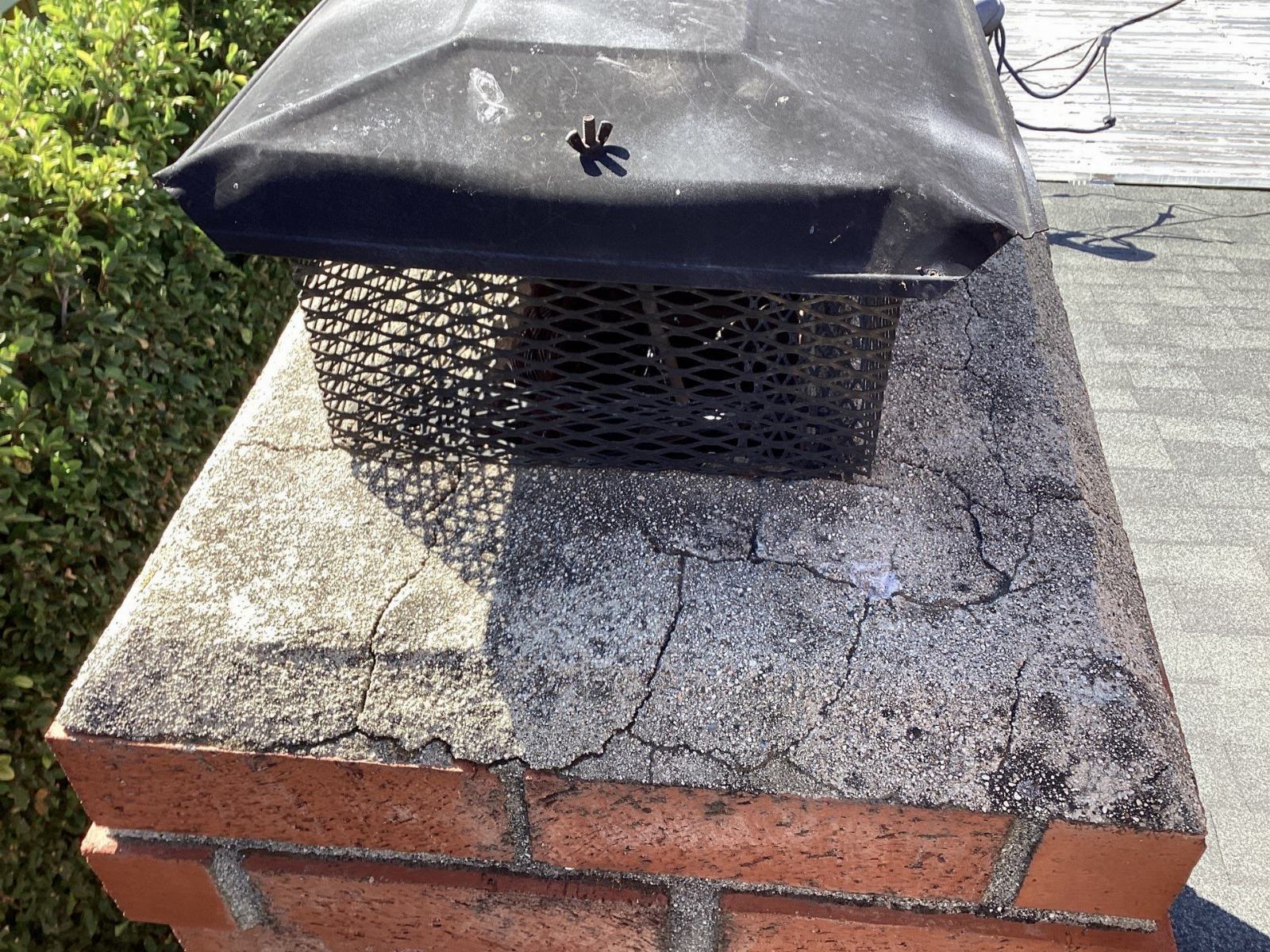Cracked chimney crown with metal cap and spark arrestor mesh in Calabasas | Roof Replacement Inc Cracked chimney crown with metal cap and spark arrestor mesh — Calabasas — Roof Replacement Inc