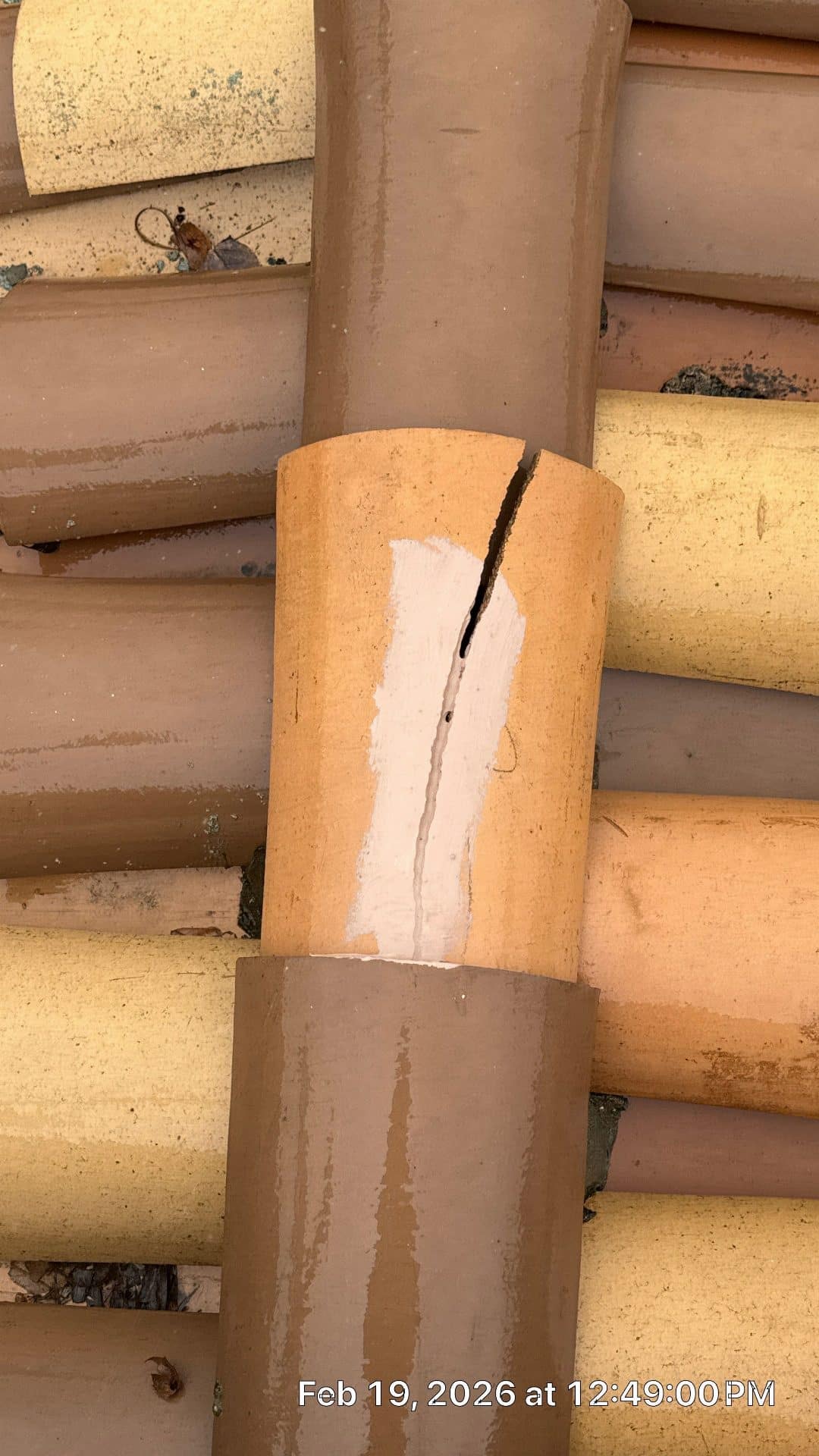 Cracked clay barrel roof tile with white caulk repair attempt — Malibu — Roof Replacement Inc
