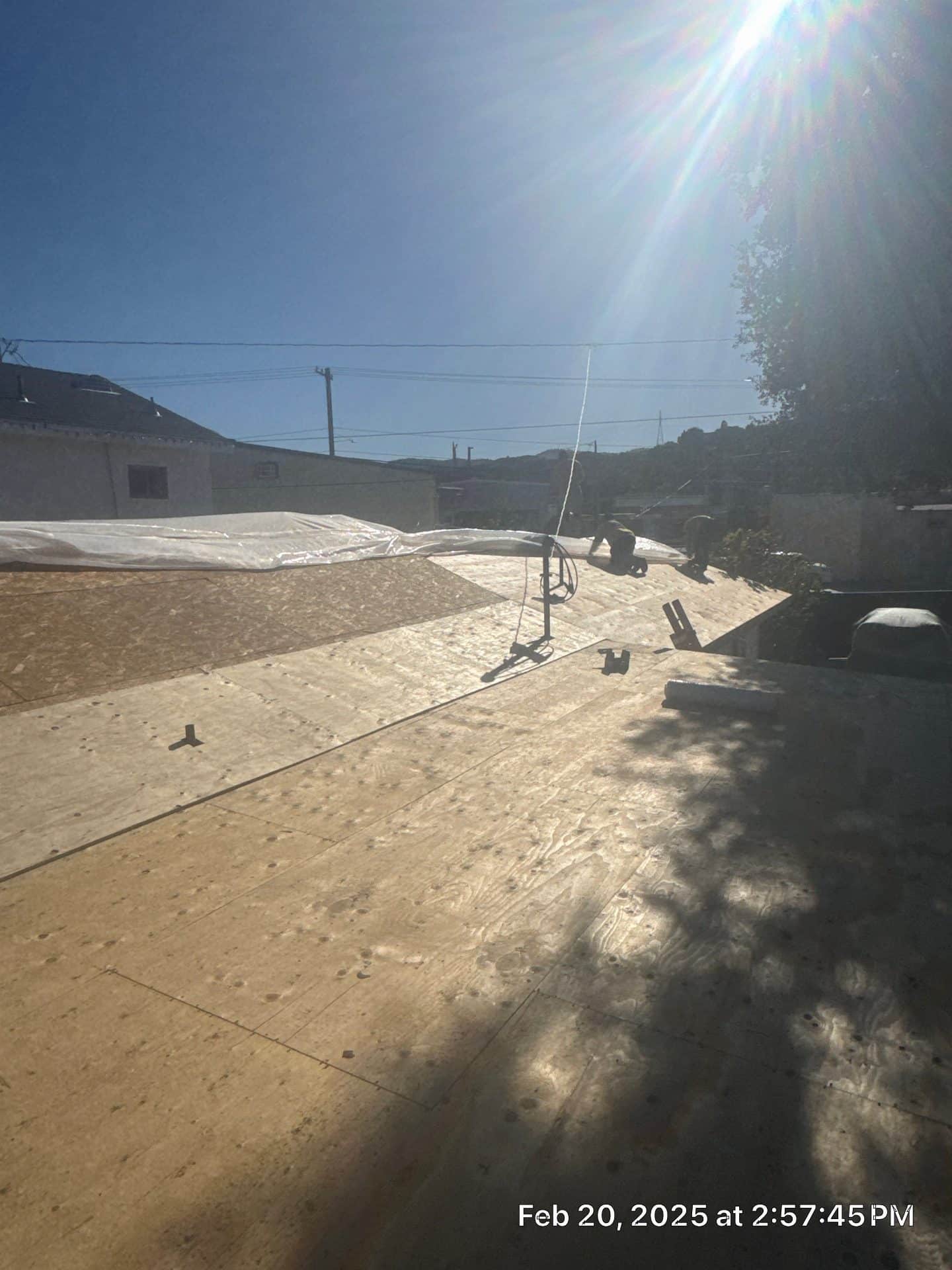 Flat roof deck with OSB sheathing, tarp, antenna mount, and worker | Roof Replacement Inc Flat roof deck with OSB sheathing, tarp, antenna mount, and worker — Roof Replacement Inc