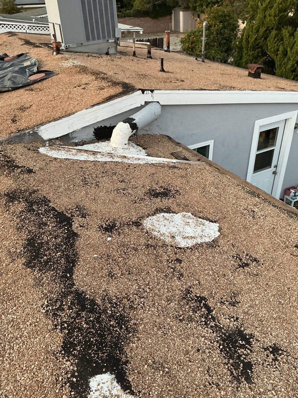 Gravel flat roof with damaged parapet, tar patches, foam sealant applied — Panorama City — Roof Replacement Inc