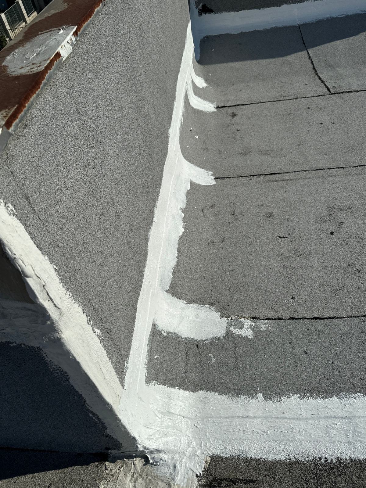 White elastomeric sealant applied to flat roof parapet corner seams in Panorama City | Roof Replacement Inc White elastomeric sealant applied to flat roof parapet corner seams — Panorama City — Roof Replacement Inc