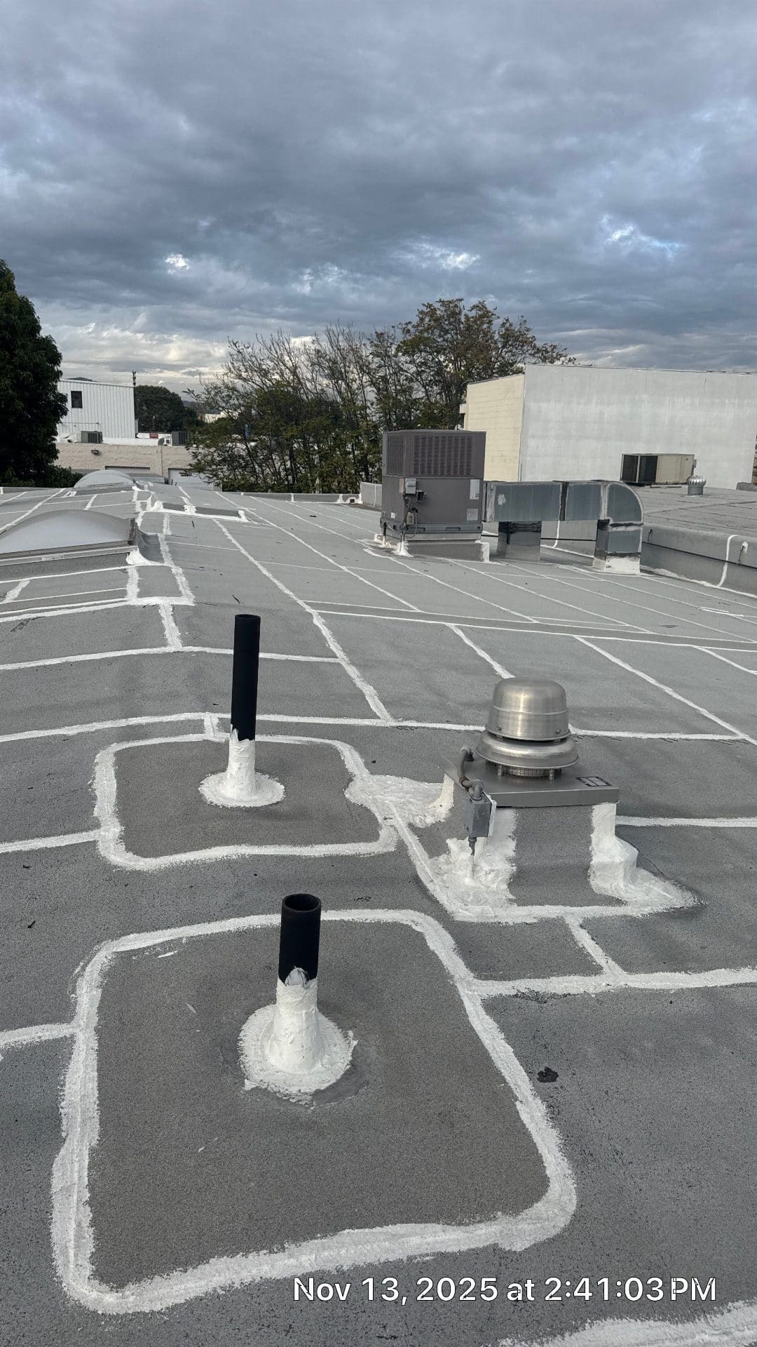 Flat roof with pipe boots, vent cap, and white sealant grid pattern in Northridge | Roof Replacement Inc Flat roof with pipe boots, vent cap, and white sealant grid pattern — Northridge — Roof Replacement Inc