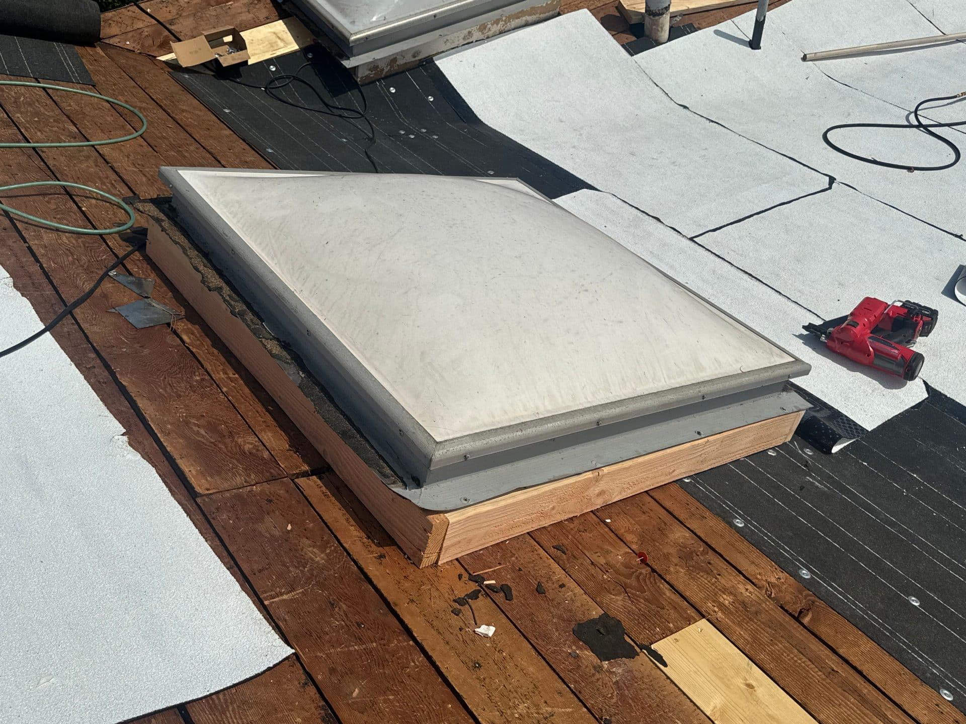 Flat roof skylight on wood curb, TPO membrane, nail gun nearby in Mar Vista | Roof Replacement Inc Flat roof skylight on wood curb, TPO membrane, nail gun nearby — Mar Vista — Roof Replacement Inc