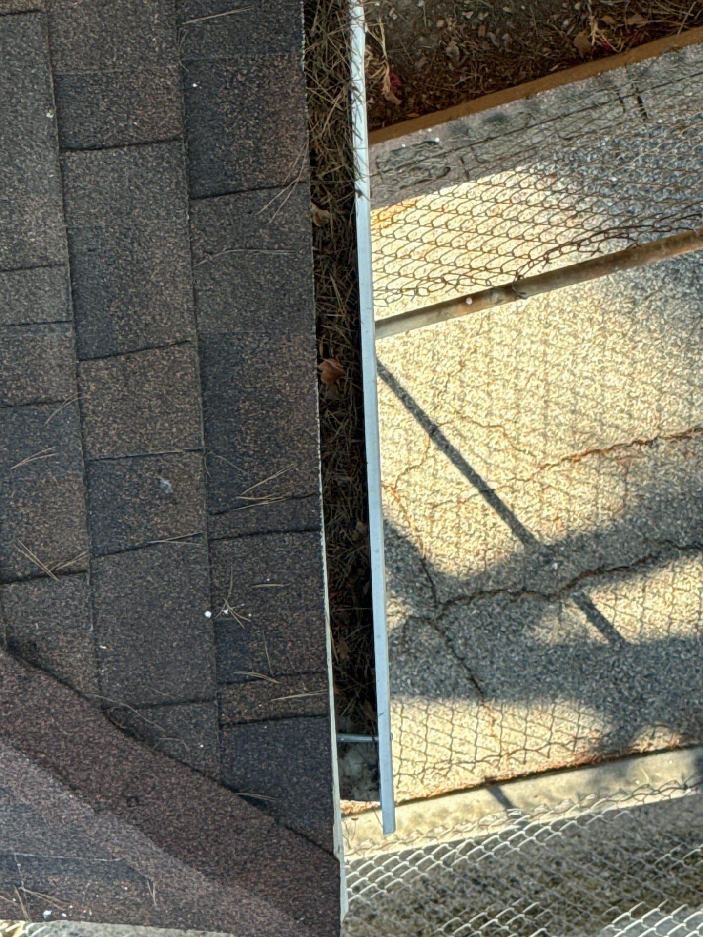 Clogged gutter with wire mesh guard, asphalt shingles visible — La Crescenta-Montrose — Roof Replacement Inc