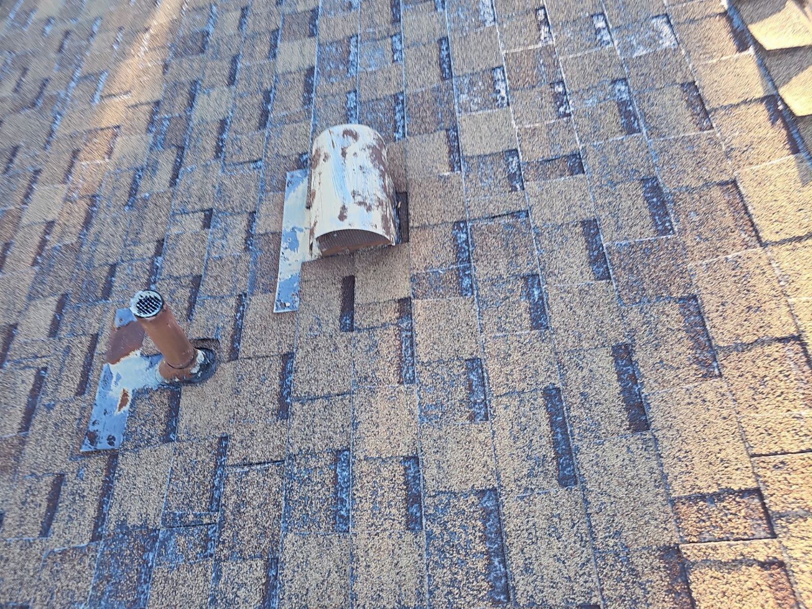 Asphalt shingle roof with rusted plumbing vent and deteriorated exhaust vent cap in Santa Clarita | Roof Replacement Inc Asphalt shingle roof with rusted plumbing vent and deteriorated exhaust vent cap — Santa Clarita — Roof Replacement Inc