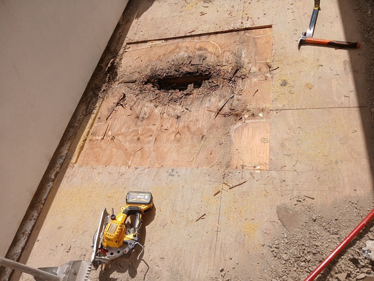 Rotted plywood roof deck with hole, circular saw and hammer visible — Studio City — Roof Replacement Inc