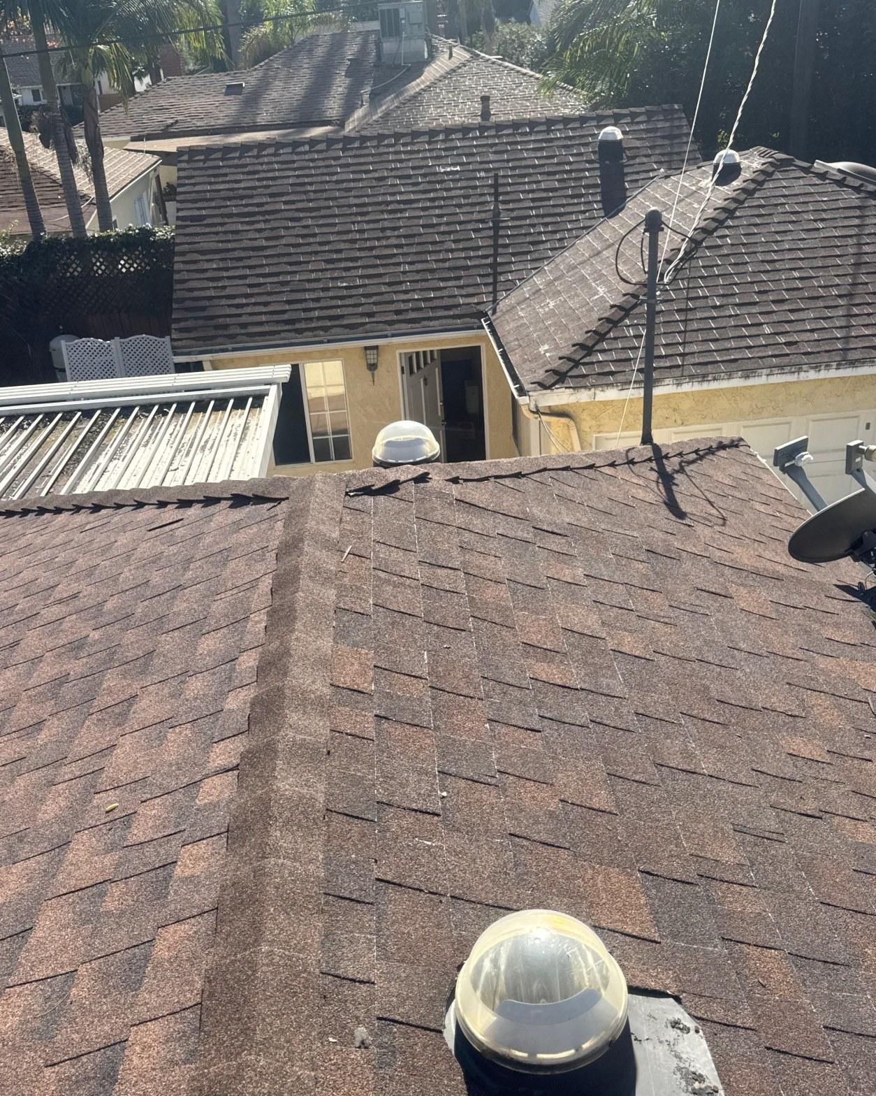 shingle-reroof-duration-cool-plus-los-angeles-3312 Aerial view of brown asphalt shingle roof with two dome skylights, satellite dish, and neighboring tile roofs.