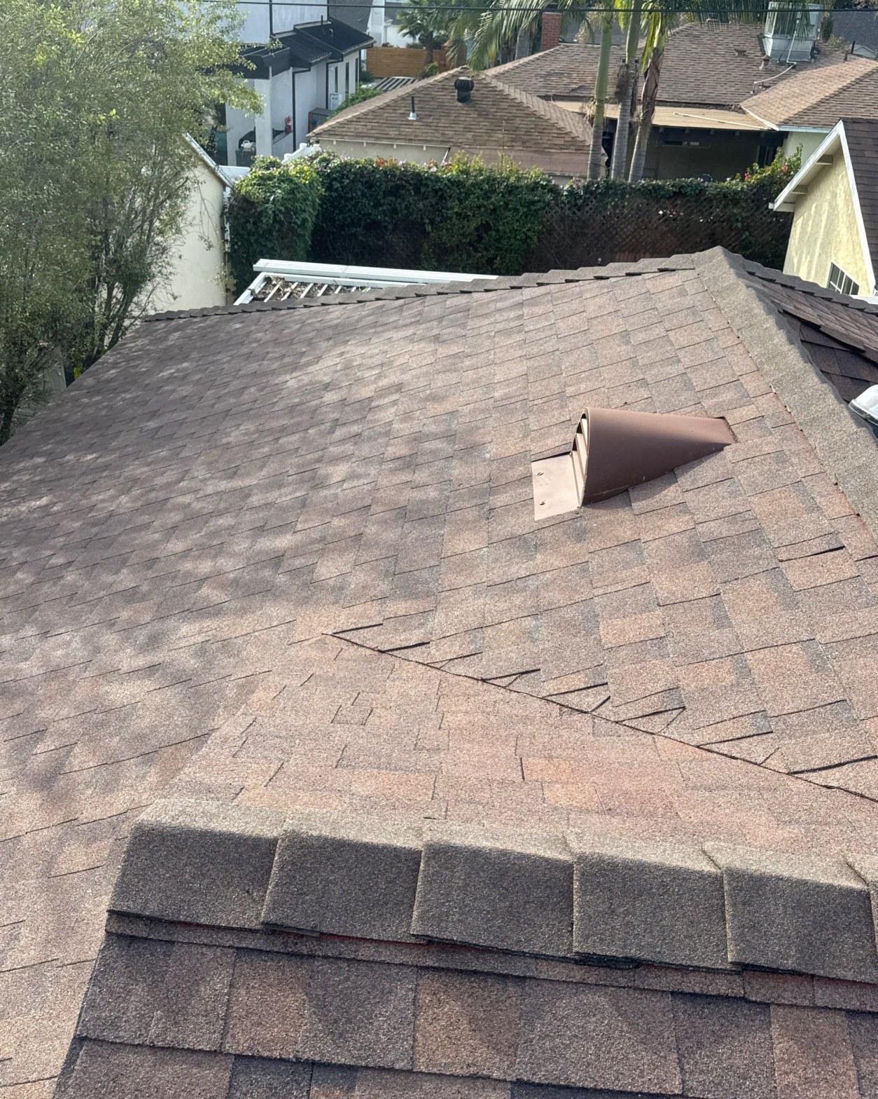 shingle-reroof-duration-cool-plus-los-angeles-3328 Torn and bent pipe boot flashing on brown asphalt shingle roof with surrounding shingle damage visible.