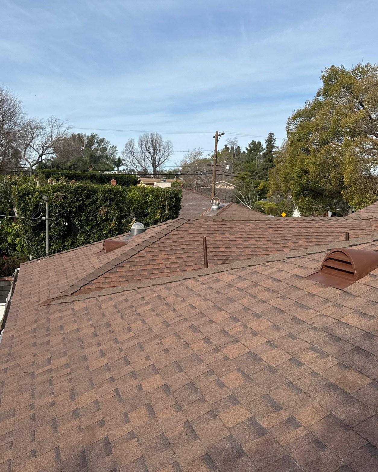 shingle-reroof-duration-cool-plus-los-angeles-3331 Newly installed brown architectural asphalt shingle roof with turbine vents and half-round exhaust vents on residential home.