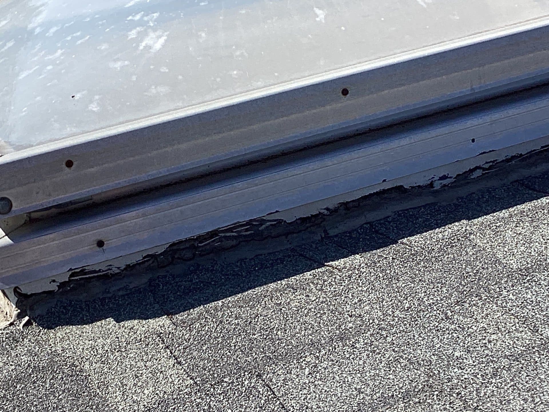 Deteriorated sealant beneath skylight aluminum frame on asphalt shingle roof in Calabasas | Roof Replacement Inc Deteriorated sealant beneath skylight aluminum frame on asphalt shingle roof — Calabasas — Roof Replacement Inc