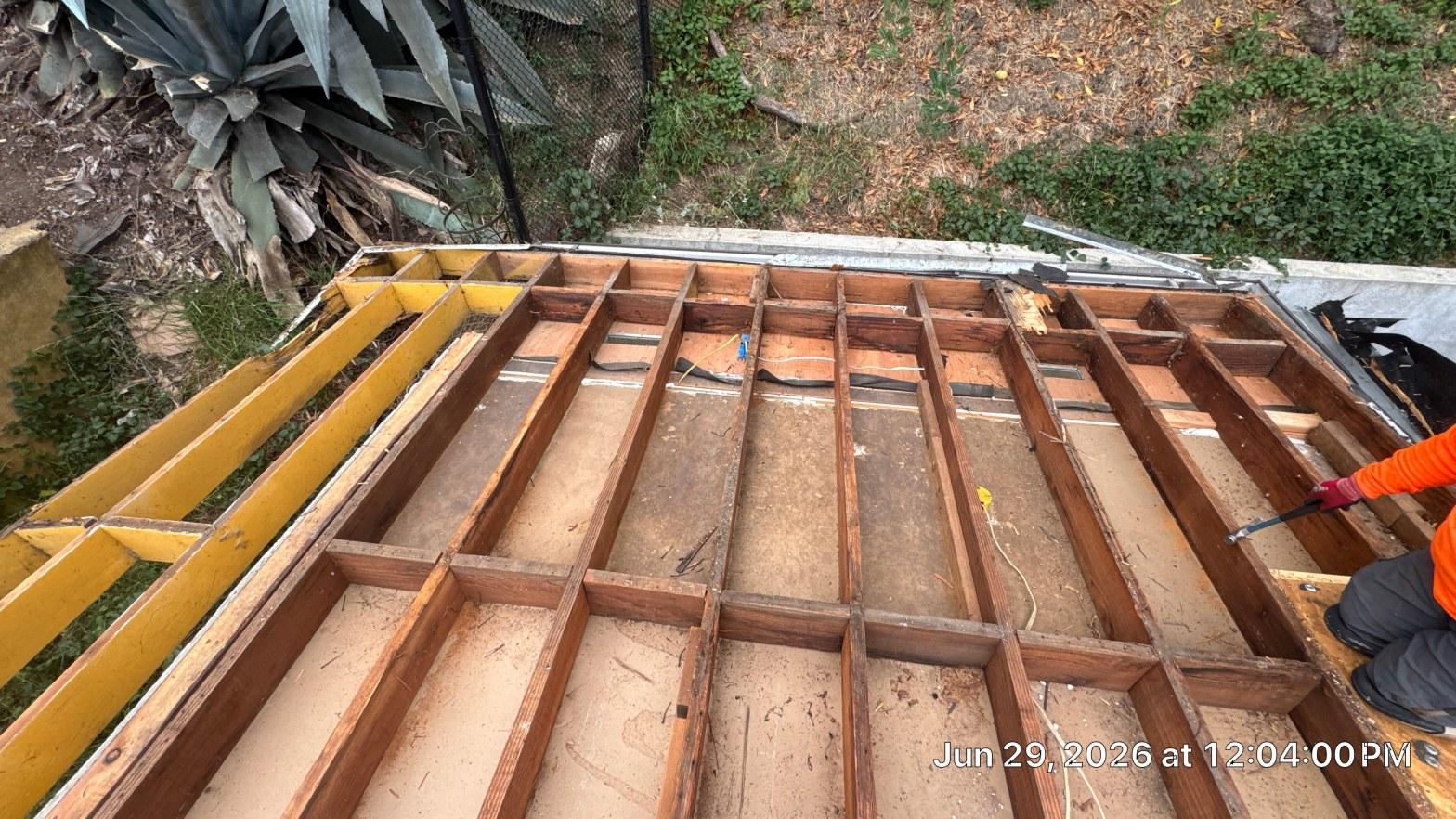 Bare wood framing joists exposed after full tearoff of failed flat roof membrane on Los Angeles County home