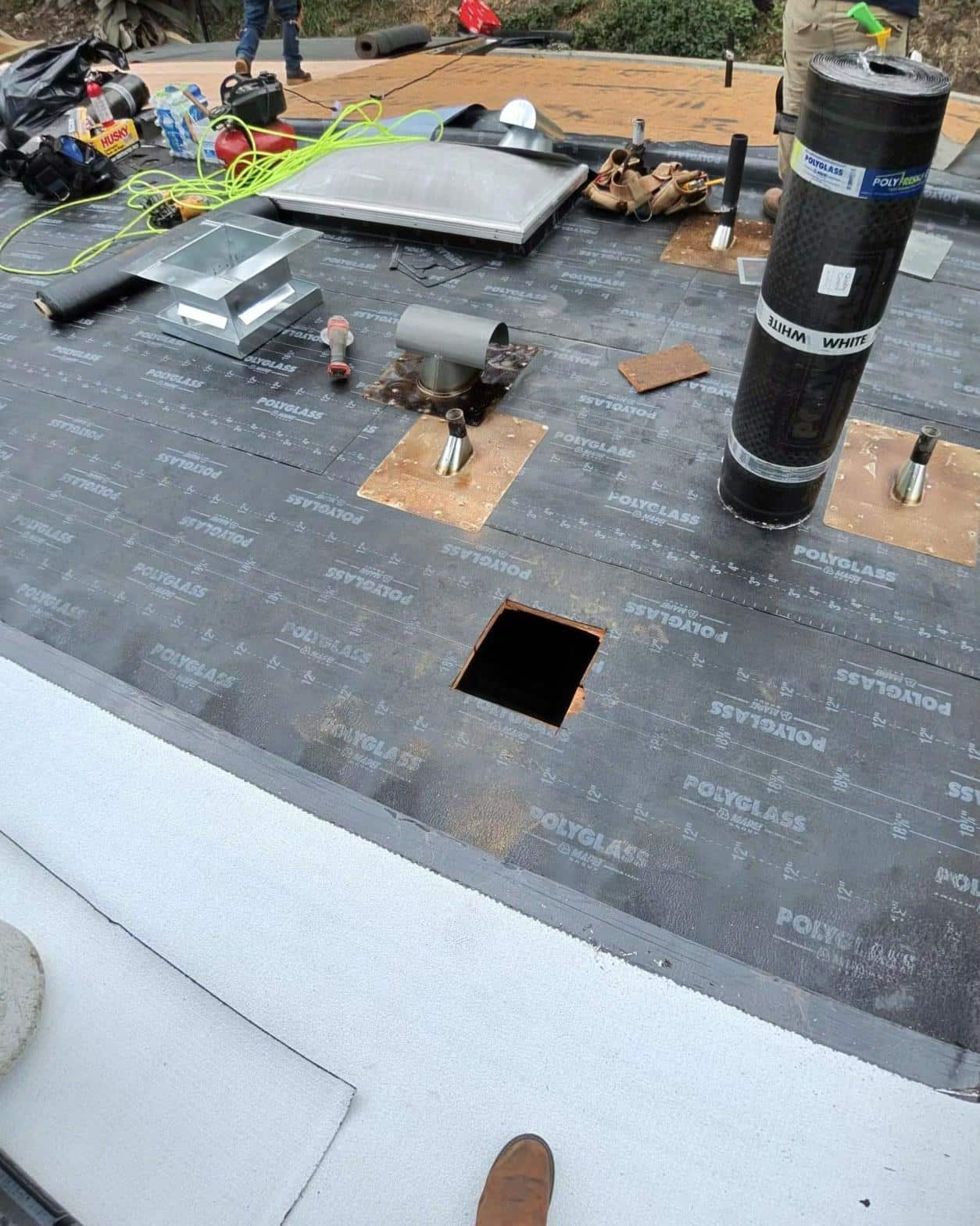 Polyglass torch down base sheet installed over new decking with skylight curb and pipe penetration flashings