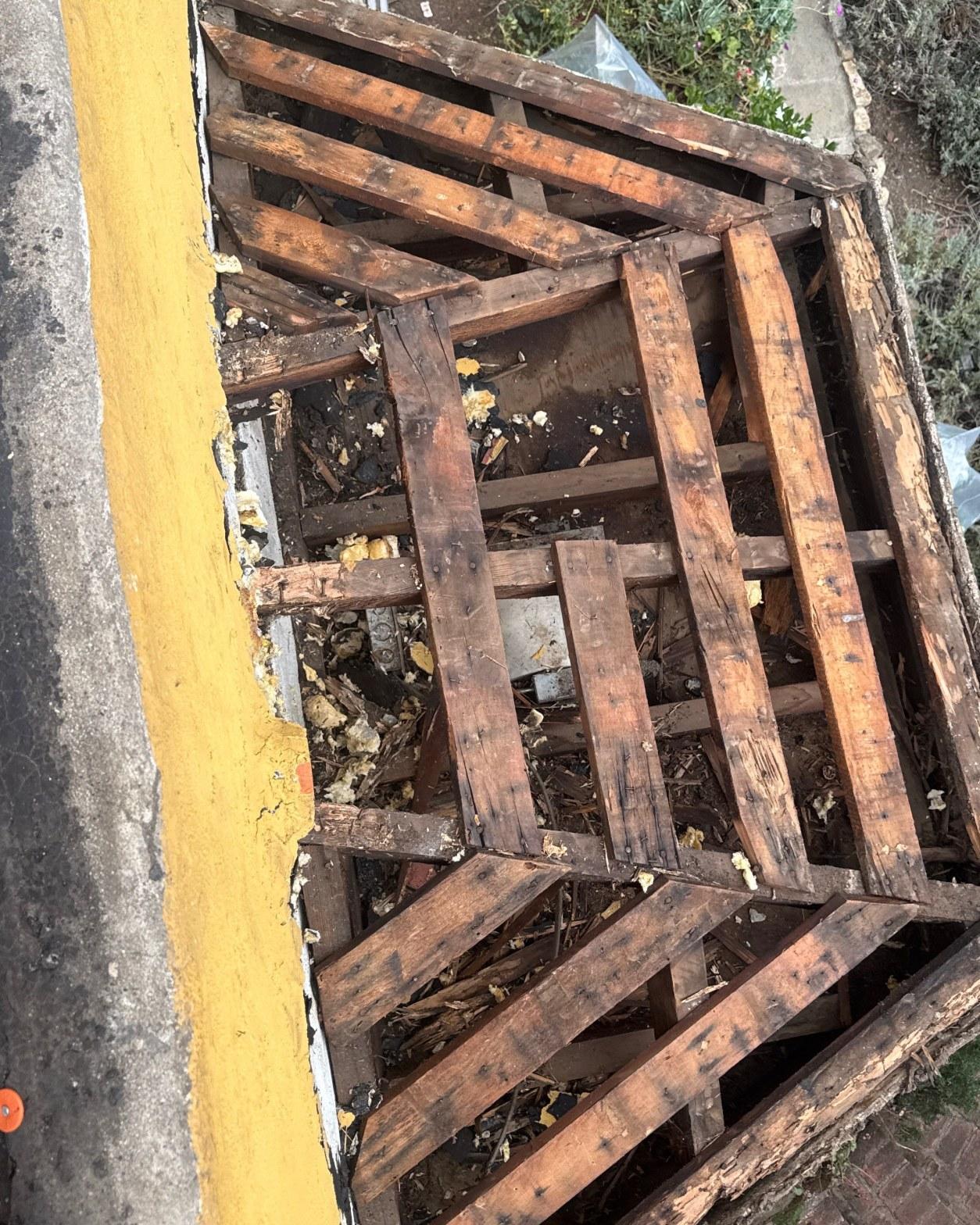torch-down-flat-roof-replacement-insulation-los-angeles-3352 Aerial view of severely deteriorated wooden roof framing with debris, decay, and missing sheathing visible from above.