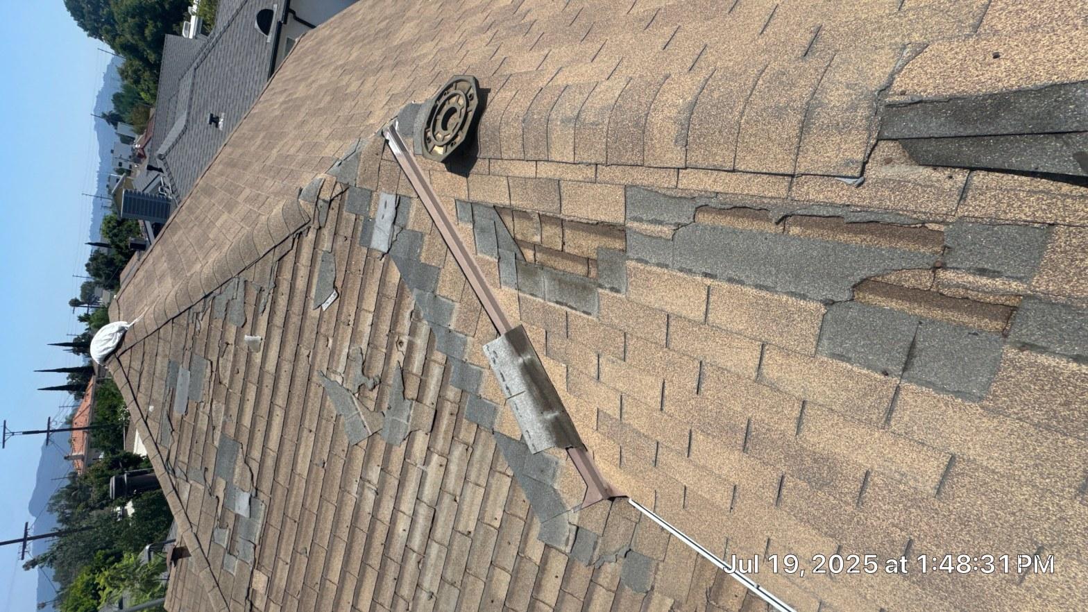 Close-up of cracked shingle tabs and failed flashing at a hip intersection, photographed July 19 2025