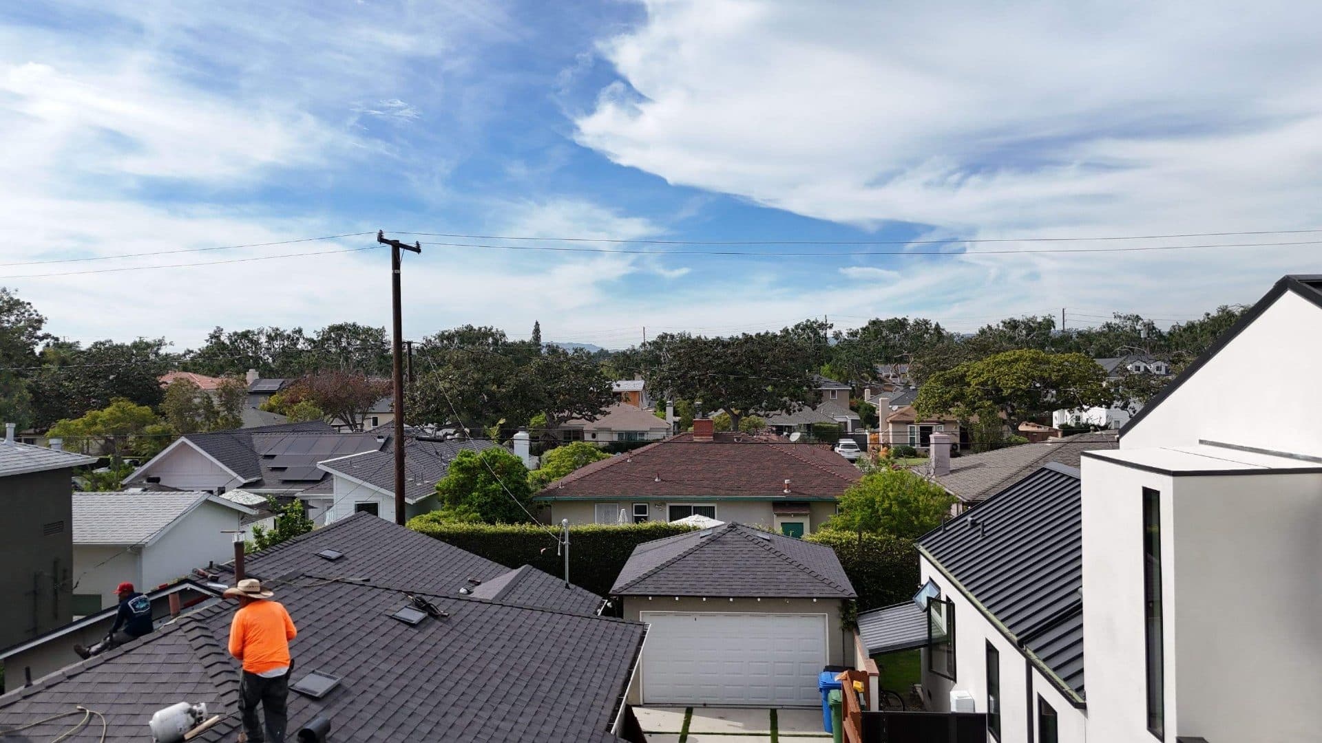 Roofers on dark asphalt shingle roof, neighborhood rooftop view — Roof Replacement Inc