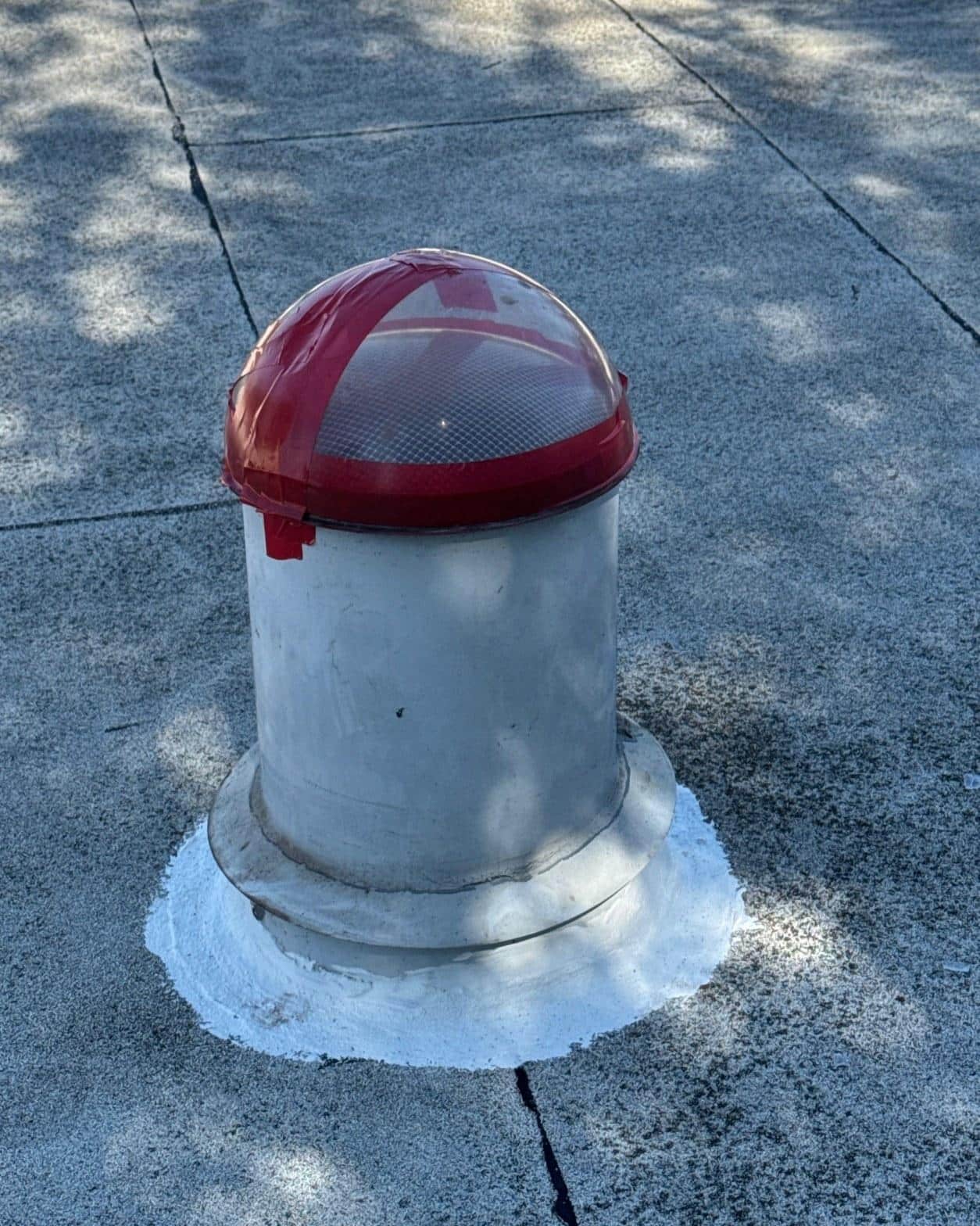Roof vent pipe with new red dome cap and elastomeric seal on flat roof section