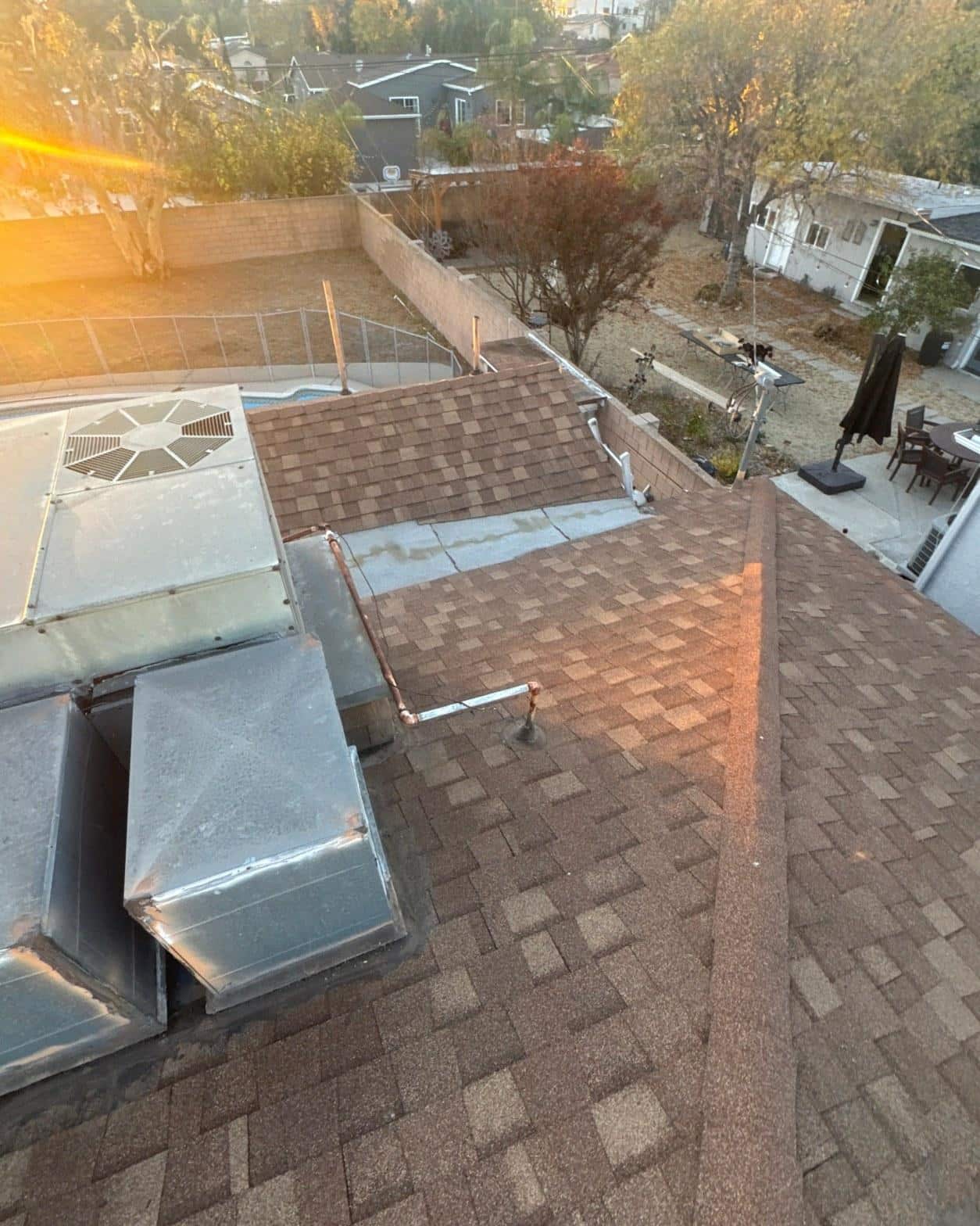 Aerial view of multi-section composition shingle roof with HVAC units and copper pipe penetrations after reroof