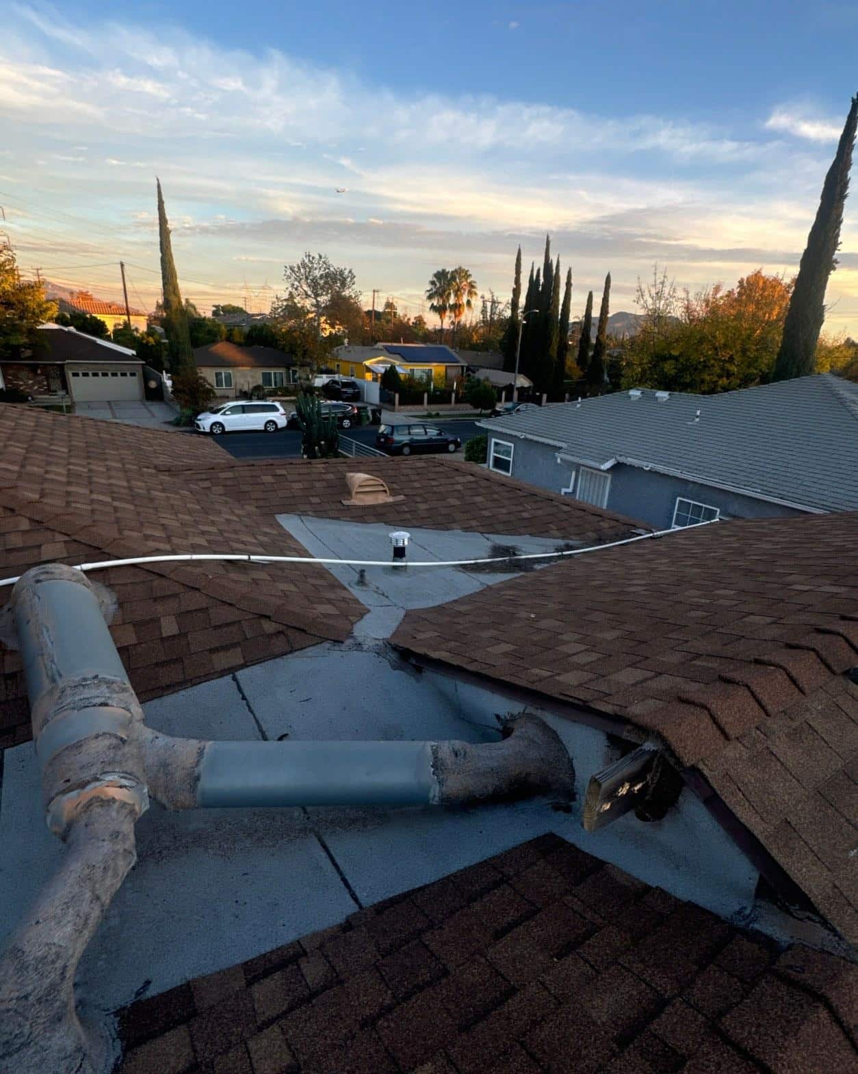 Deteriorated pipe boot flashings and open valley junction on aging composition shingle roof before replacement