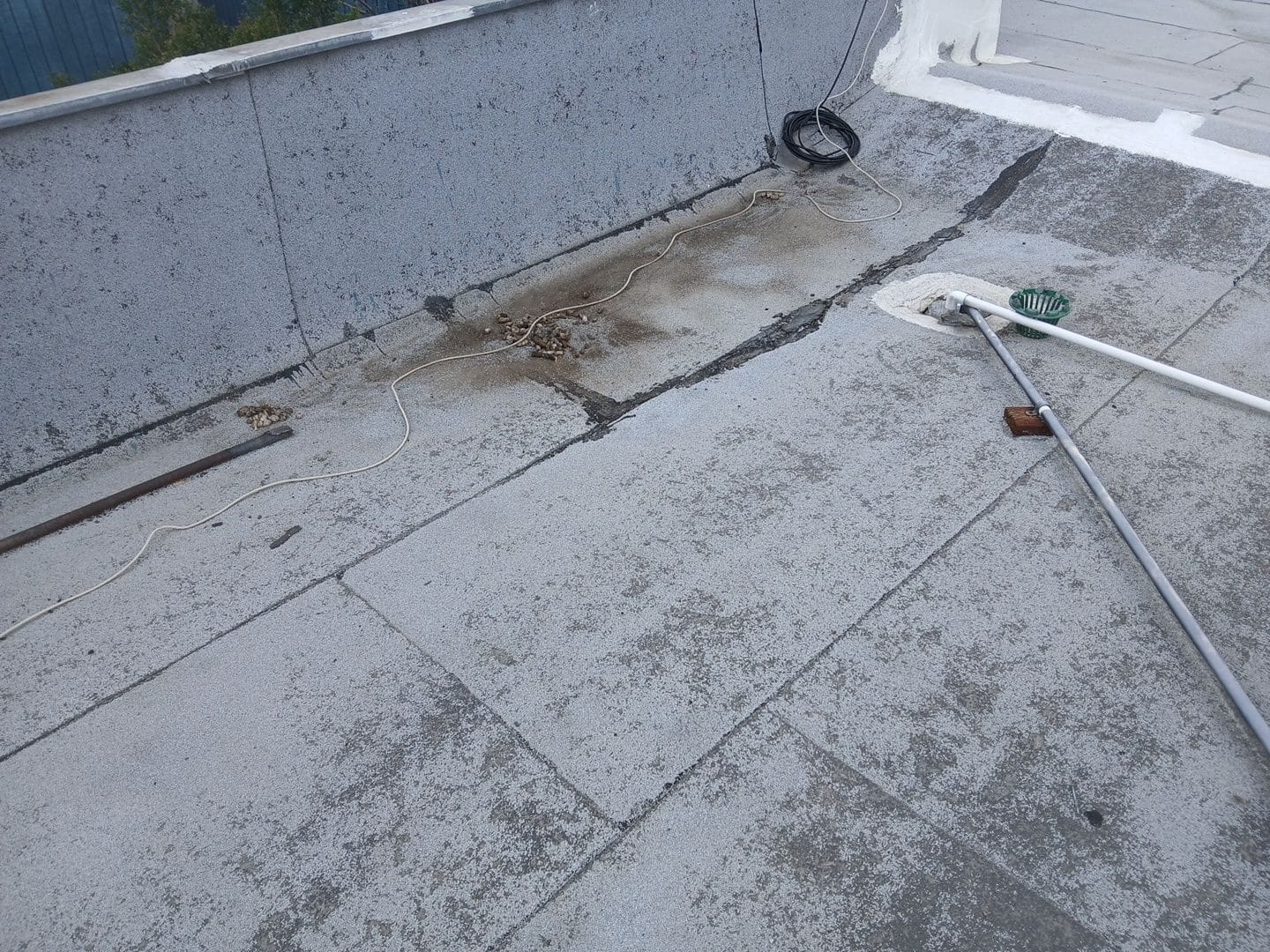Flat roof with torch-on membrane, open seams, drain, and tools — Van Nuys — Roof Replacement Inc
