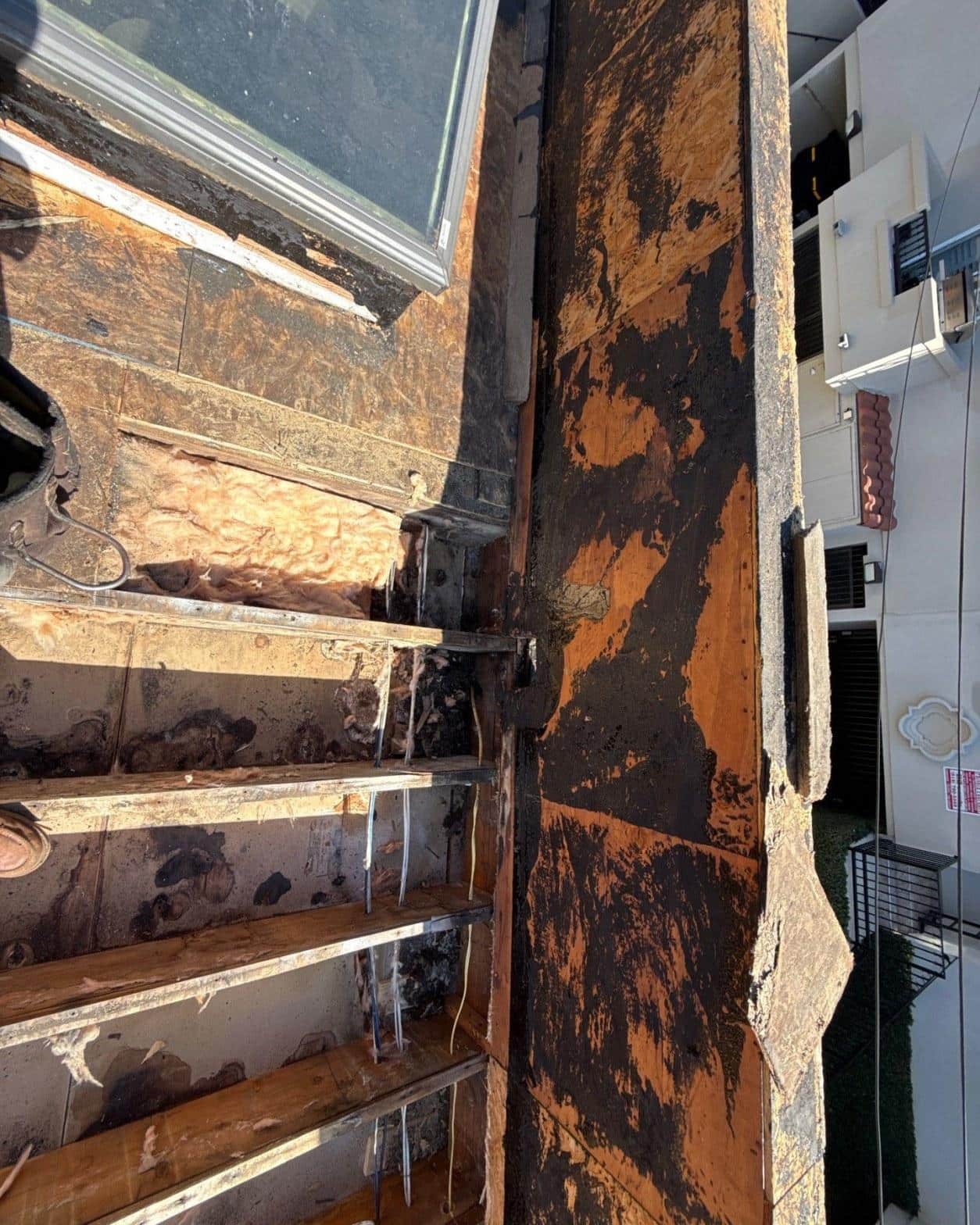 Exposed rotted joist ends and blackened OSB decking revealed after