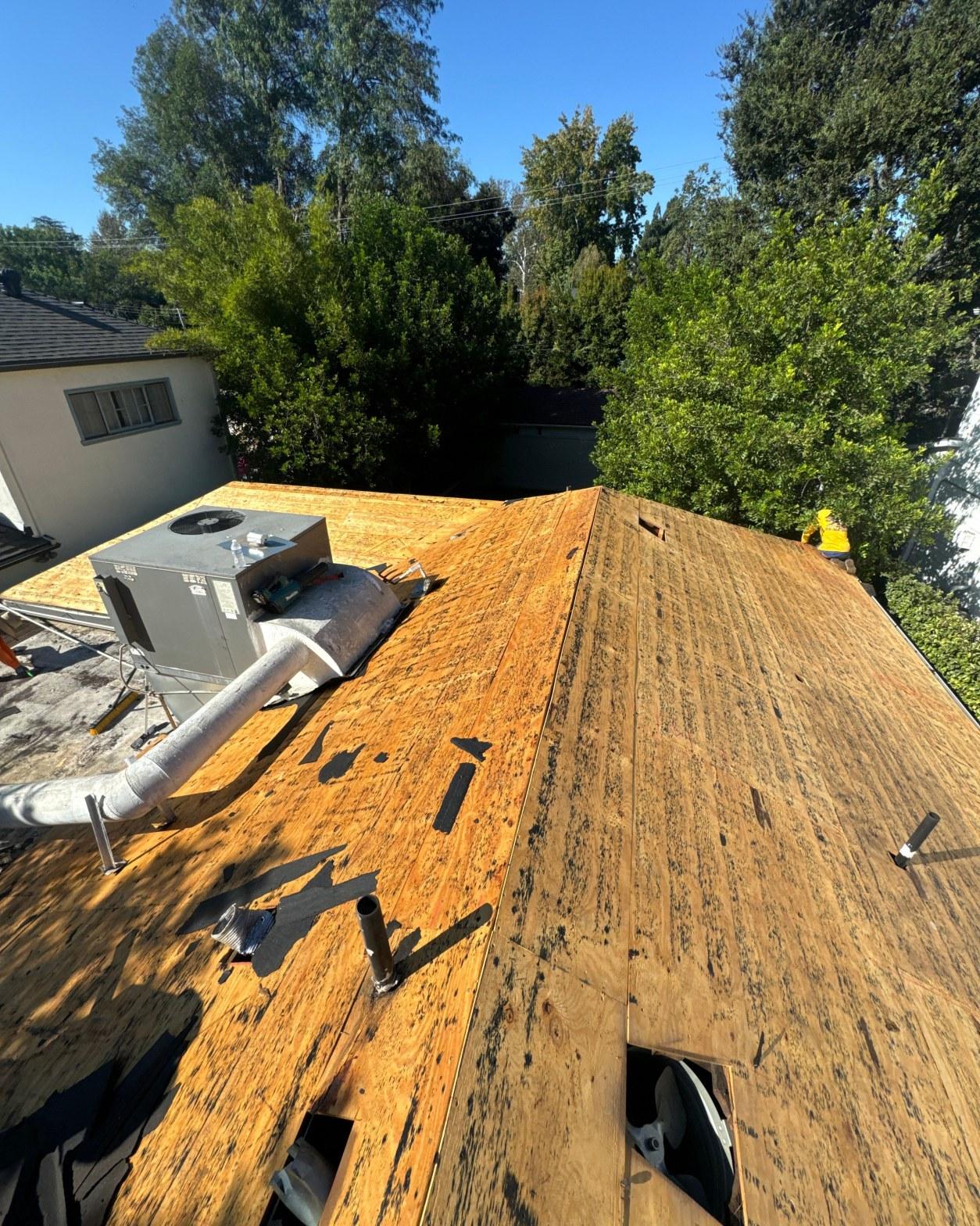 Bare plywood roof deck with HVAC unit exposed after full shingle tear-off on a San Fernando Valley home