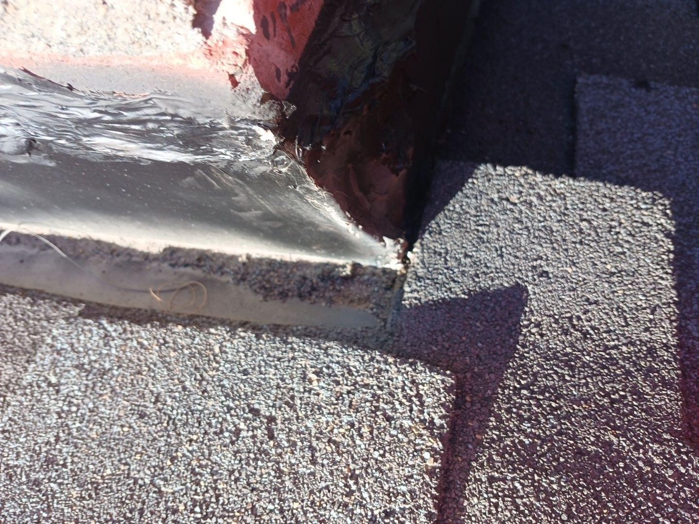 Failed aluminum tape and roofing cement at chimney corner step flashing transition on hillside home roof