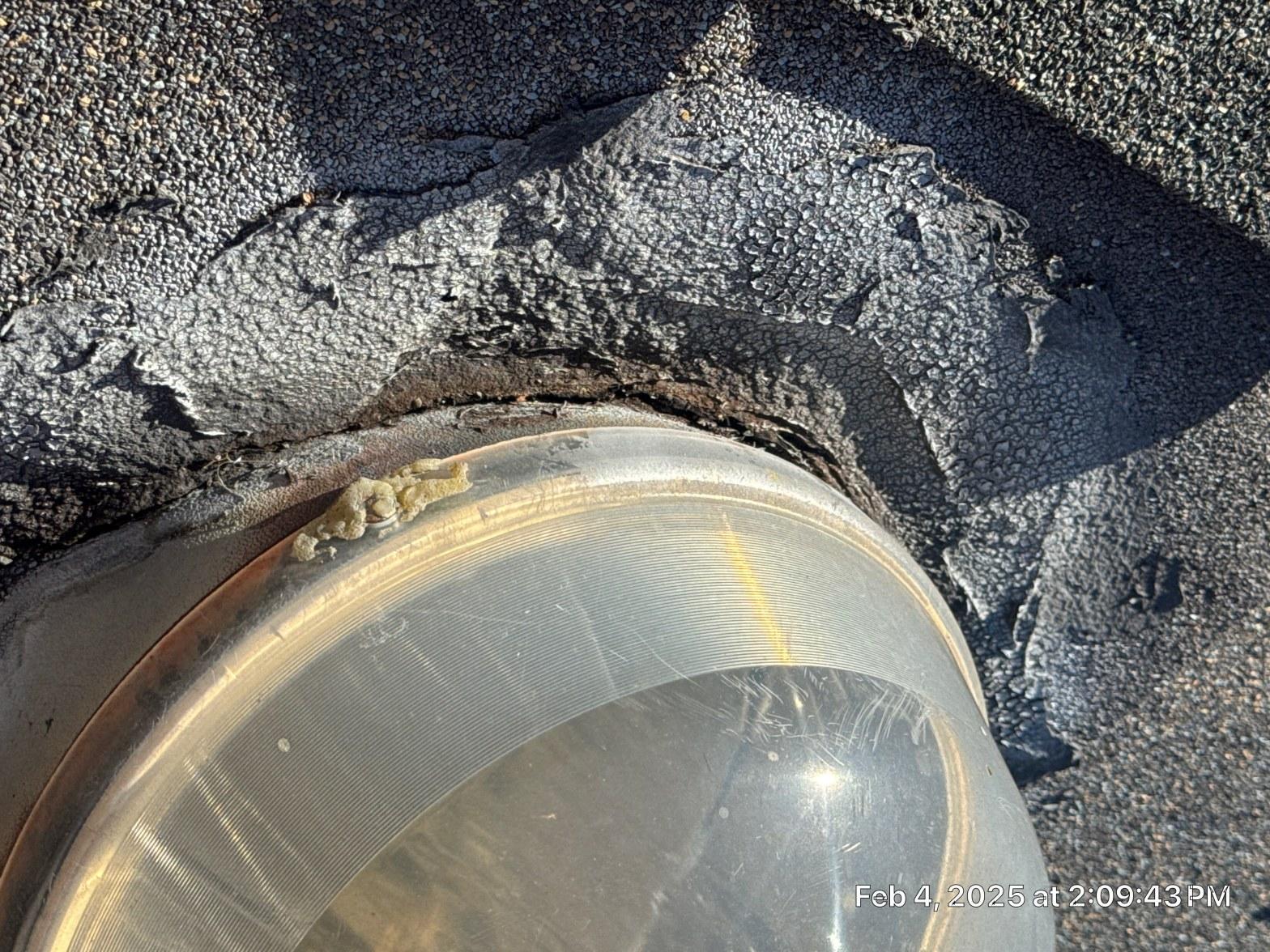 Cracked and lifted roofing cement boot seal around tubular skylight dome penetration on asphalt shingle roof