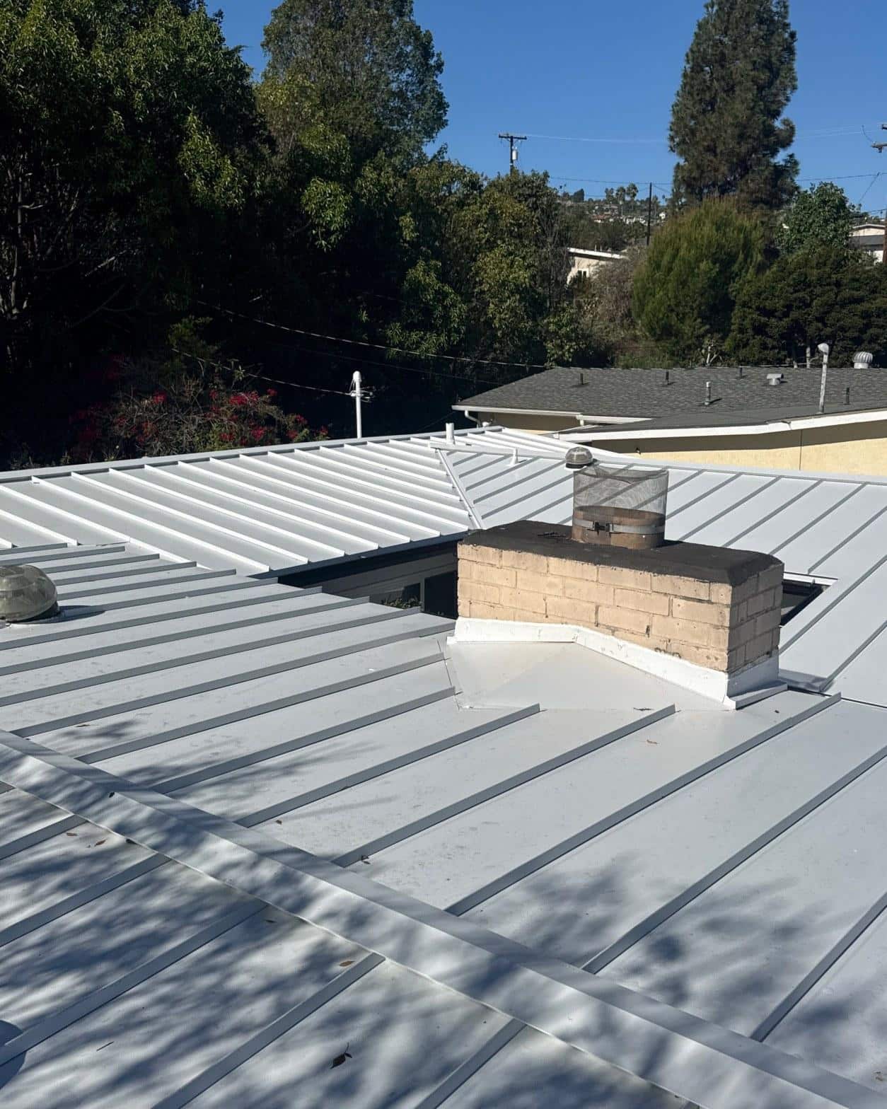 mid-century-home-standing-seam-metal-roof-skip-sheathing-4393 Completed standing-seam metal roof in cool gray with chimney flashing and reset dome skylights on mid-century courtyard home