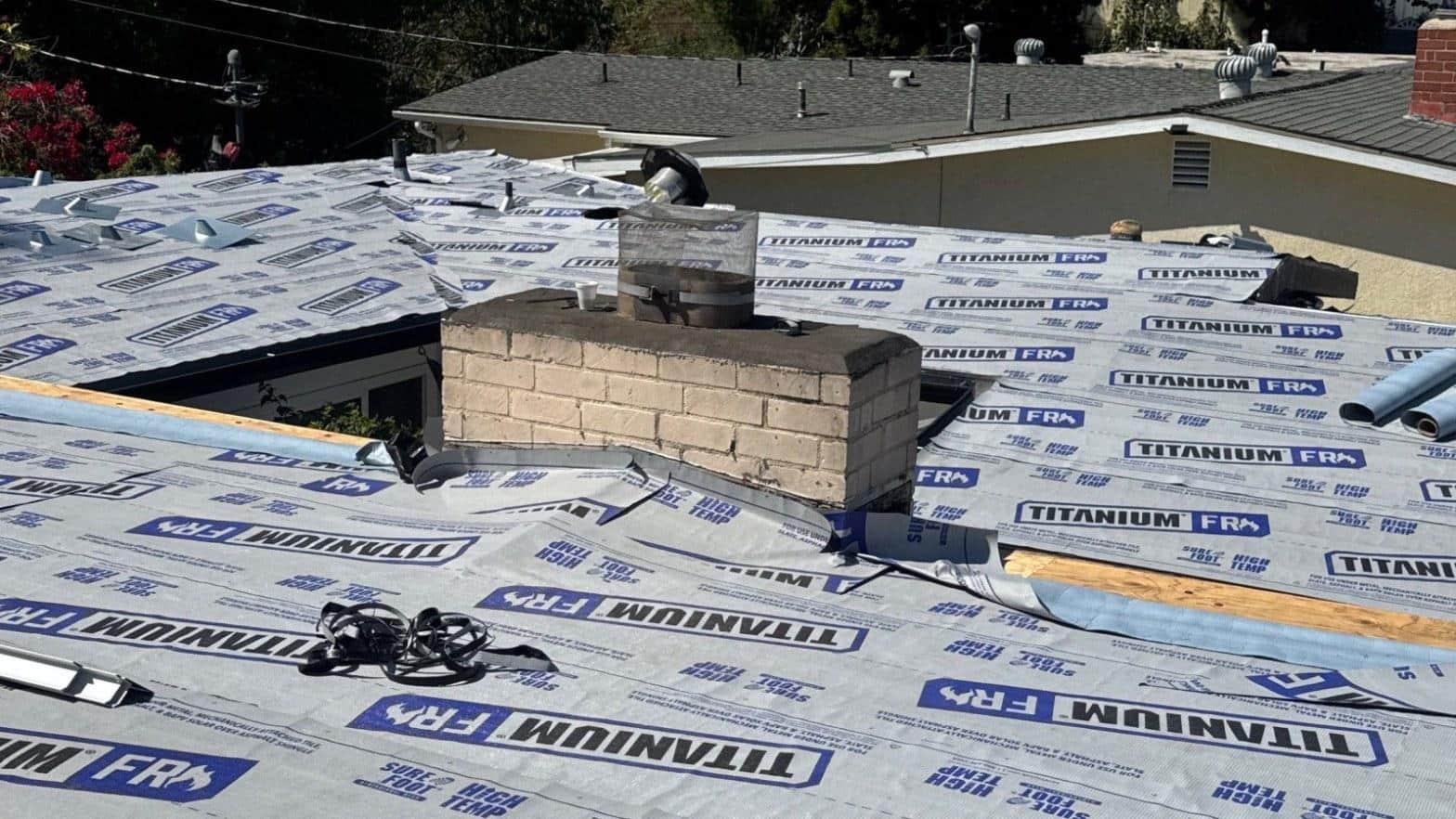 Titanium FR synthetic high-temperature underlayment covering the new plywood deck, with the brick chimney flashed in