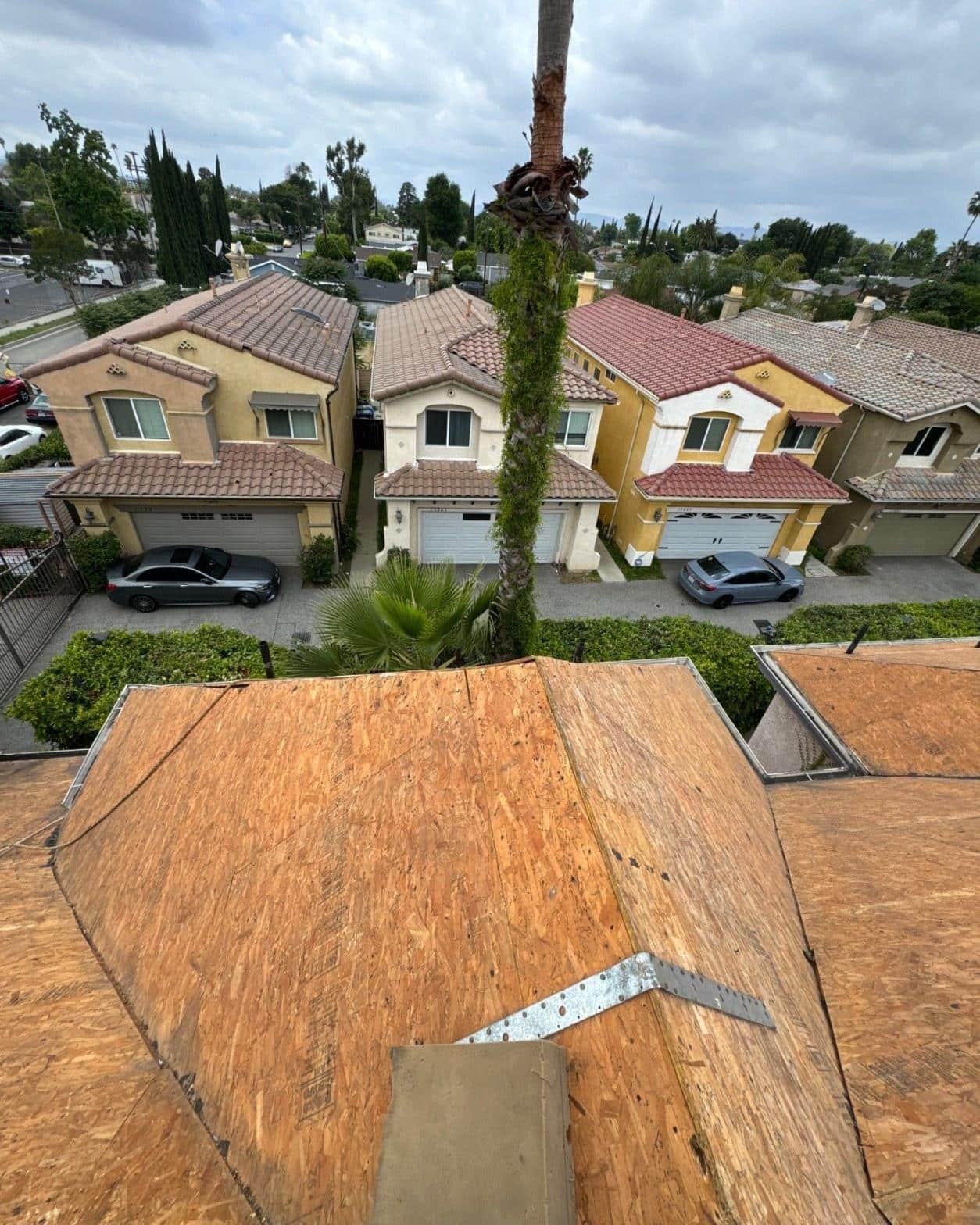 Aerial view of new OSB roof decking with hurricane tie clips installed on a two-story multi-unit residential building