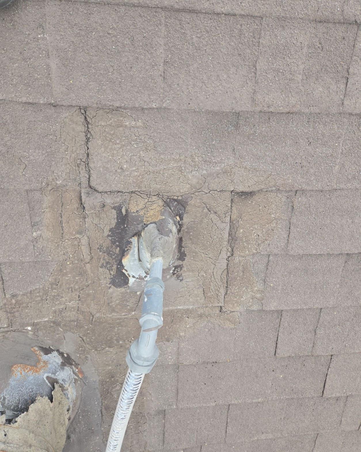Failed roofing cement and cracked shingles around a conduit penetration beneath a solar panel mounting foot