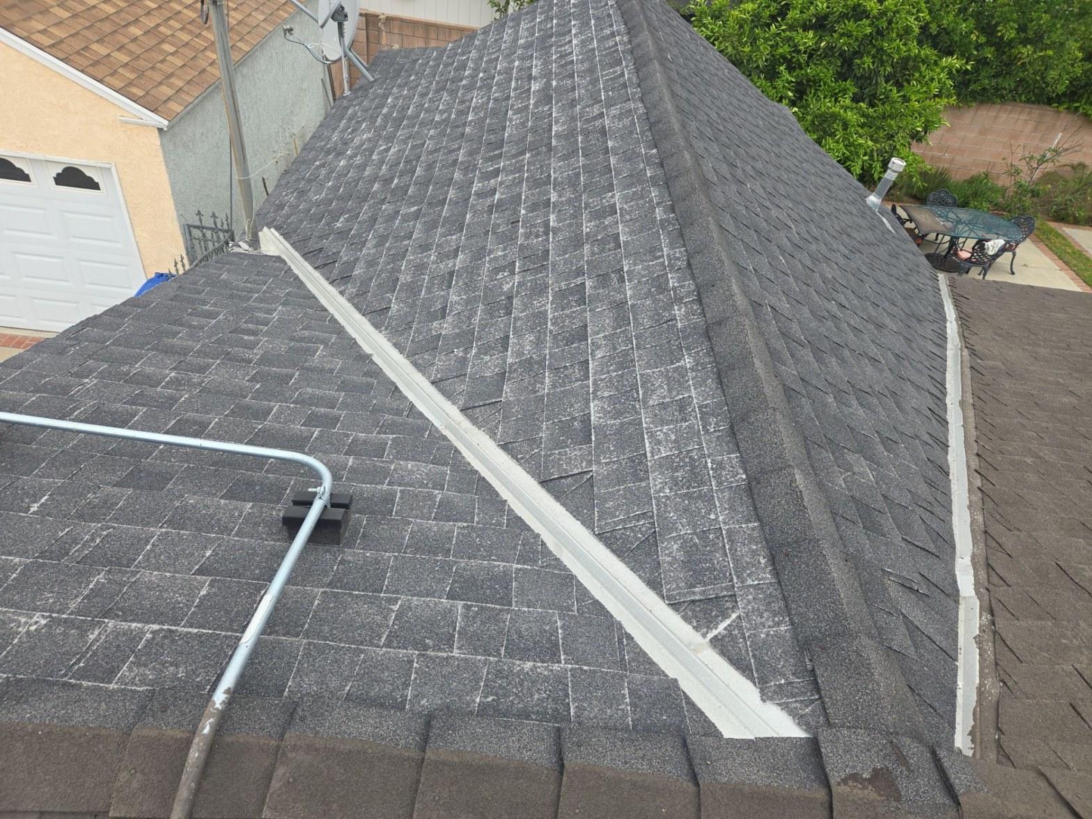 Wide view of a San Fernando Valley home's asphalt shingle roof showing severe granule loss and chalking on hip and ridge lines