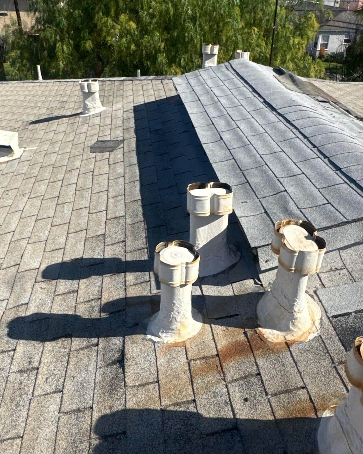 Wide view of finished shingle field with properly seated vent jacks and clean ridge after full reroof completion
