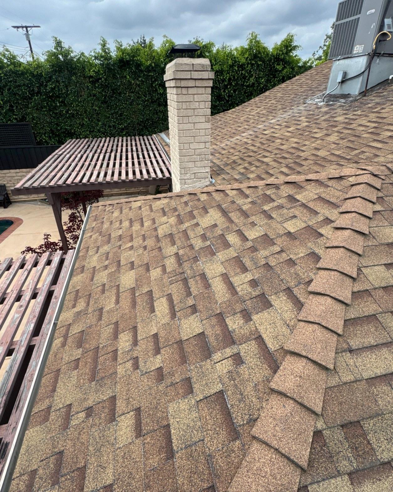 Completed architectural shingle reroof with rebuilt fascia and chimney flashing on residential home