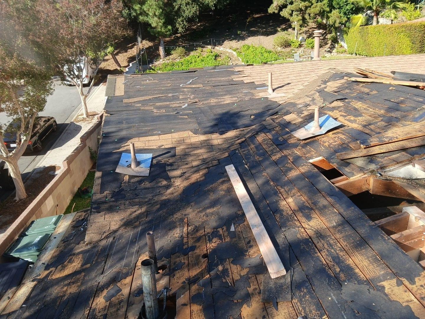 Roof stripped to bare aged wood decking with cracked boards and pipe vents exposed during LA County reroof tear-off