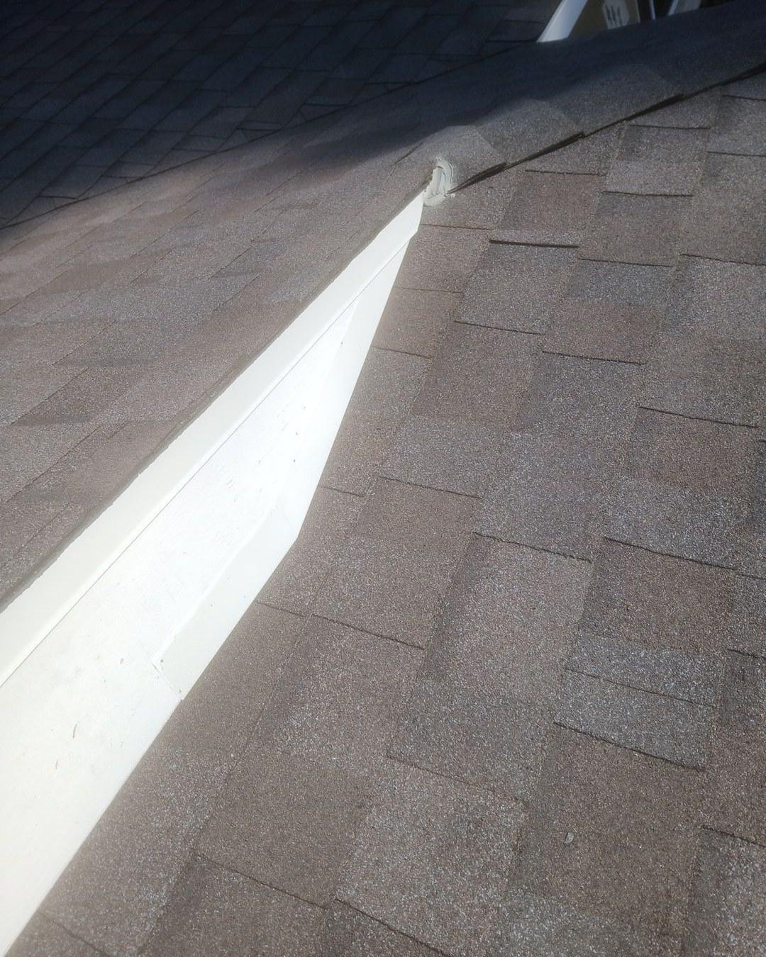 shingle-reroof-monrovia-3409 White aluminum gutter running along brown asphalt shingle roof edge with sealant at joint, residential roofing.