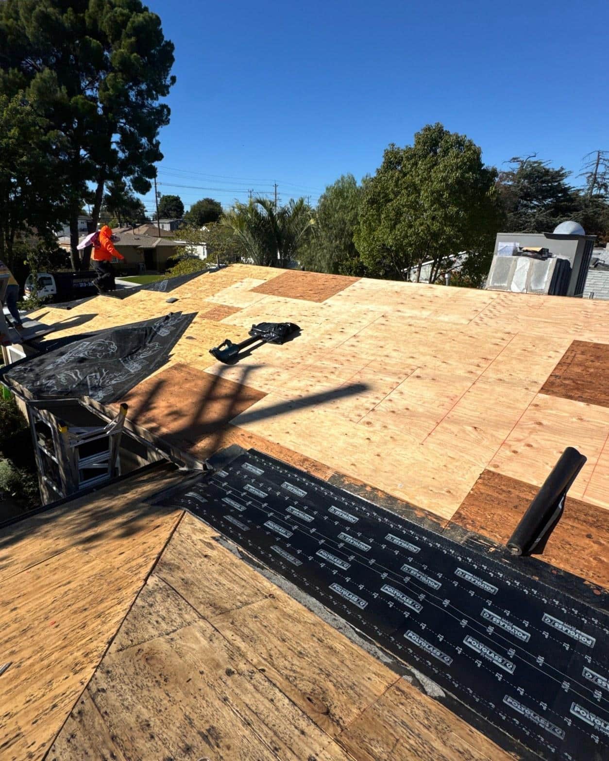Roof tear-off in progress showing new OSB decking patches and Polyglass underlayment being installed on a Southern California home