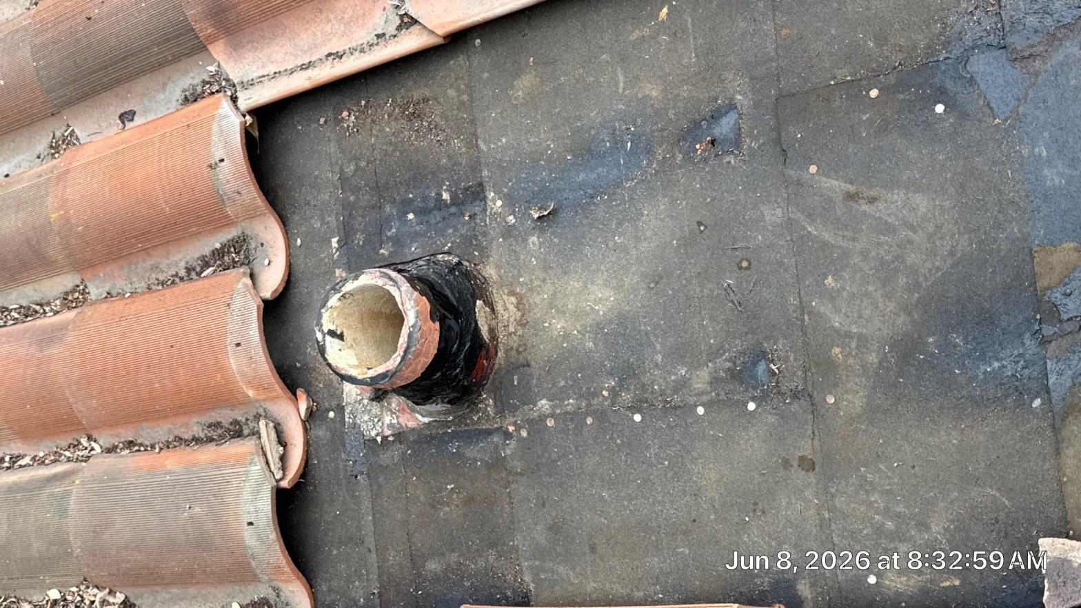Failed pipe boot flashing with cracked rubber collar and no seal remaining on aged felt underlayment under clay tile roof