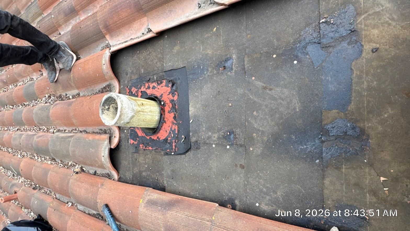 tile-roof-repair-vent-flashing-san-gabriel-3432 Cracked and failing rubber pipe boot flashing on flat roof section bordered by terracotta clay roof tiles.